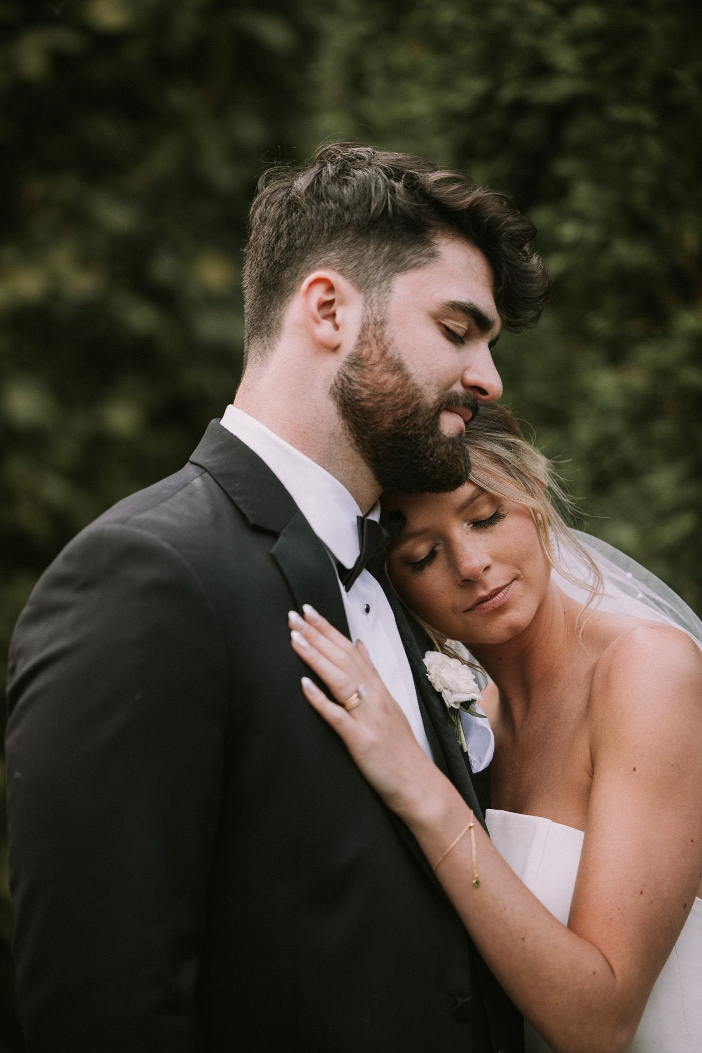 Newlywed couple shares intimate moment outdoors with bride's hand on groom's chest during wedding photo session.