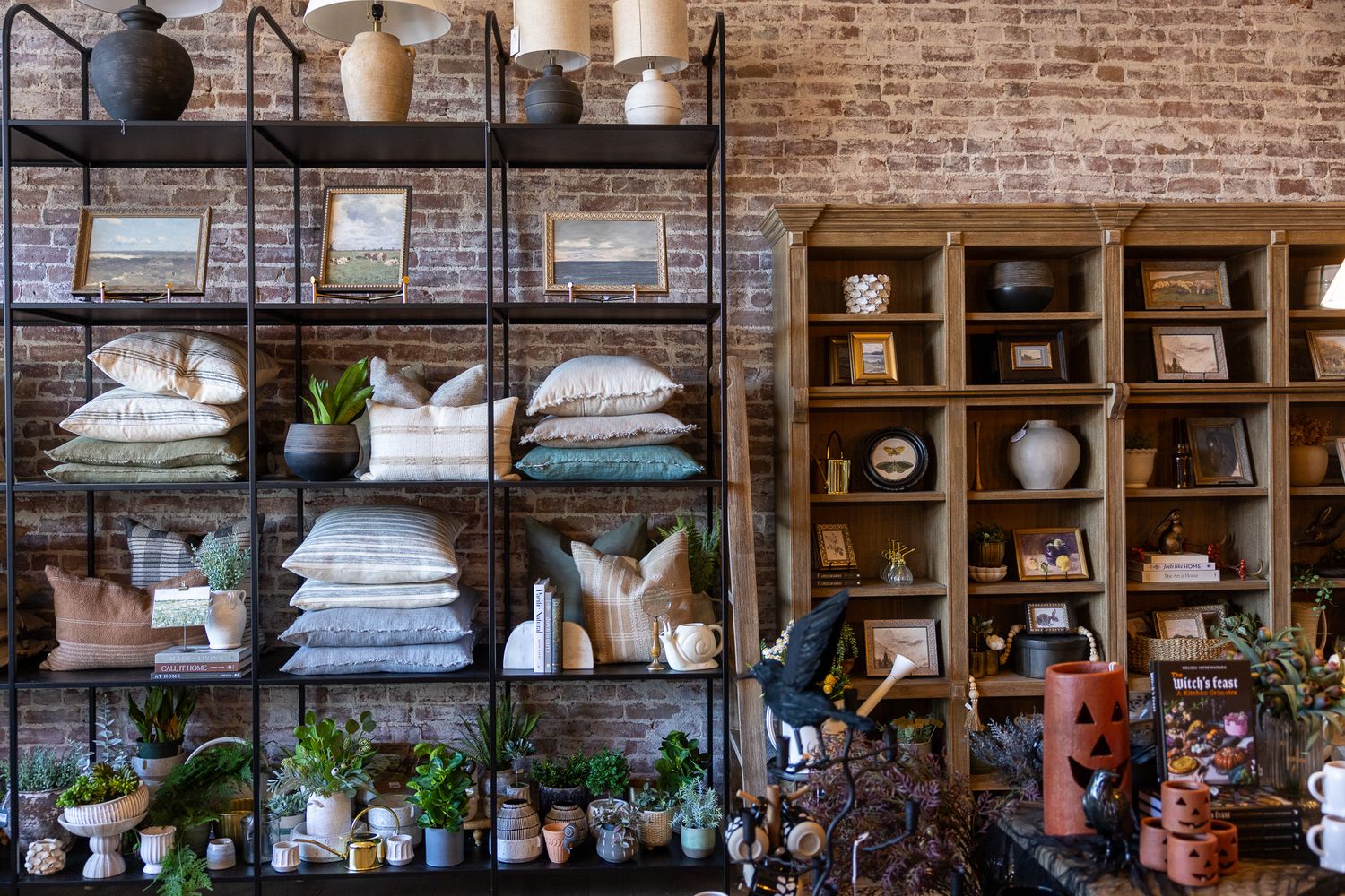 Modern loft cafe interior with vintage hanging lamps, exposed brick walls, and rustic wood shelving displaying pottery.