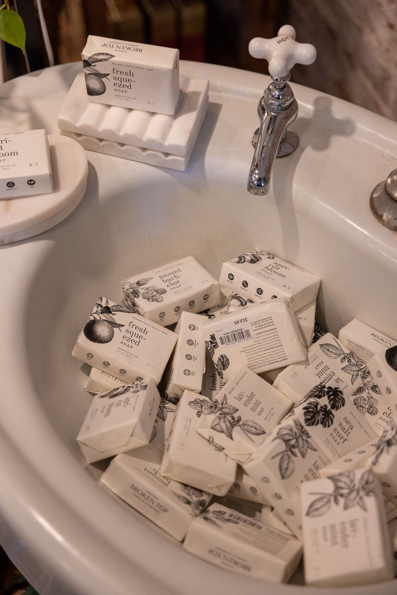 Multiple small white soap bars with printed designs arranged in a white ceramic sink.