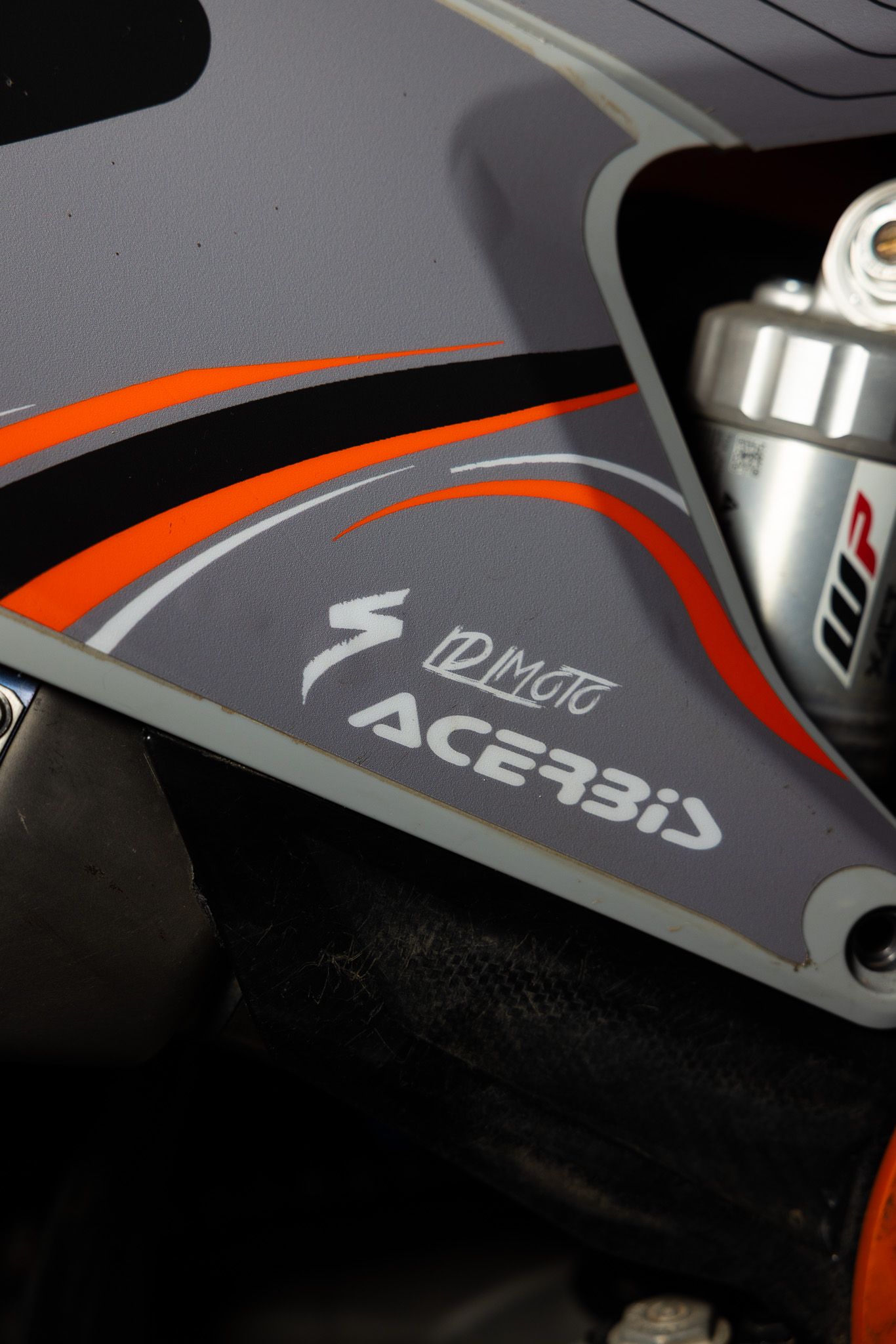 Close-up shot of sleek sports equipment with orange and gray design details showing partial logo markings.