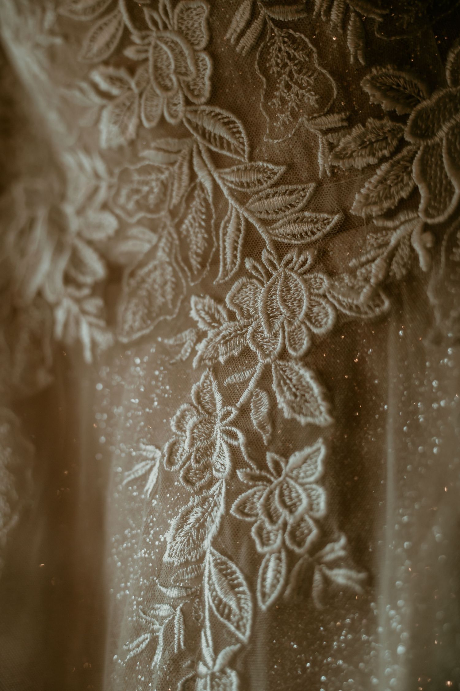 Close-up detail of intricate floral lace embroidery on a bridal wedding gown.