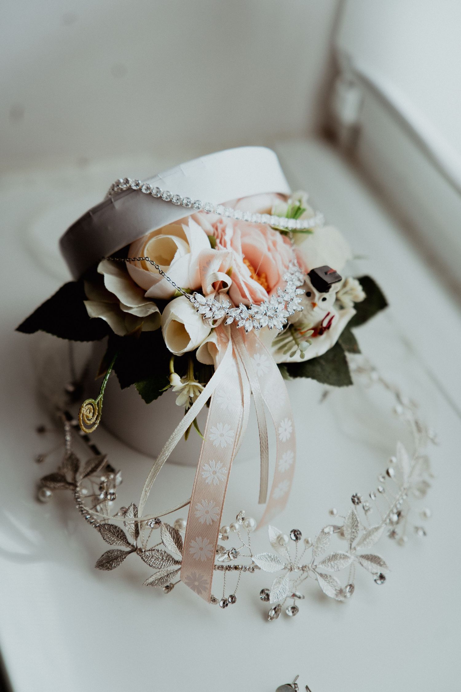 Elegant wedding corsage with pink roses and ribbon beside a crystal floral hair vine.