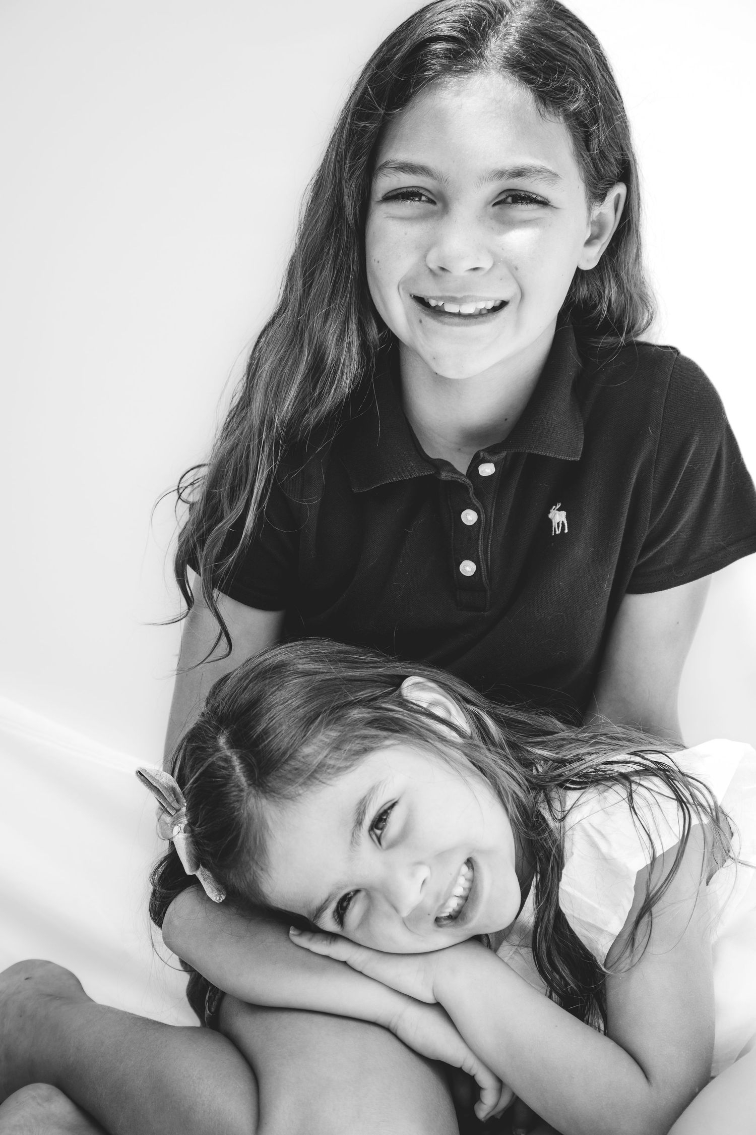 Black and white portrait of two smiling people with long dark hair in a casual intimate pose.