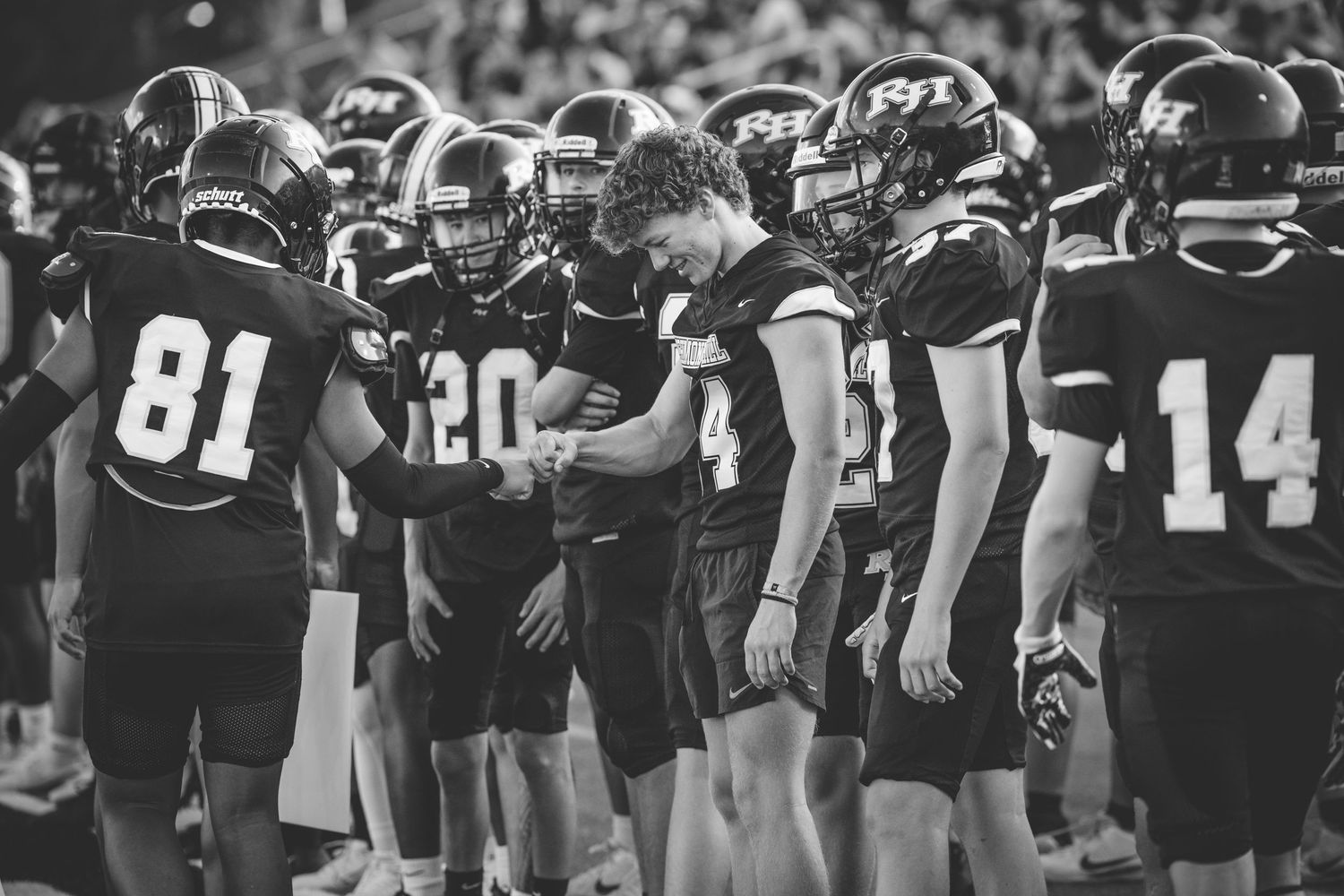 Football players line up on a field during a game with multiple players visible in black uniforms.