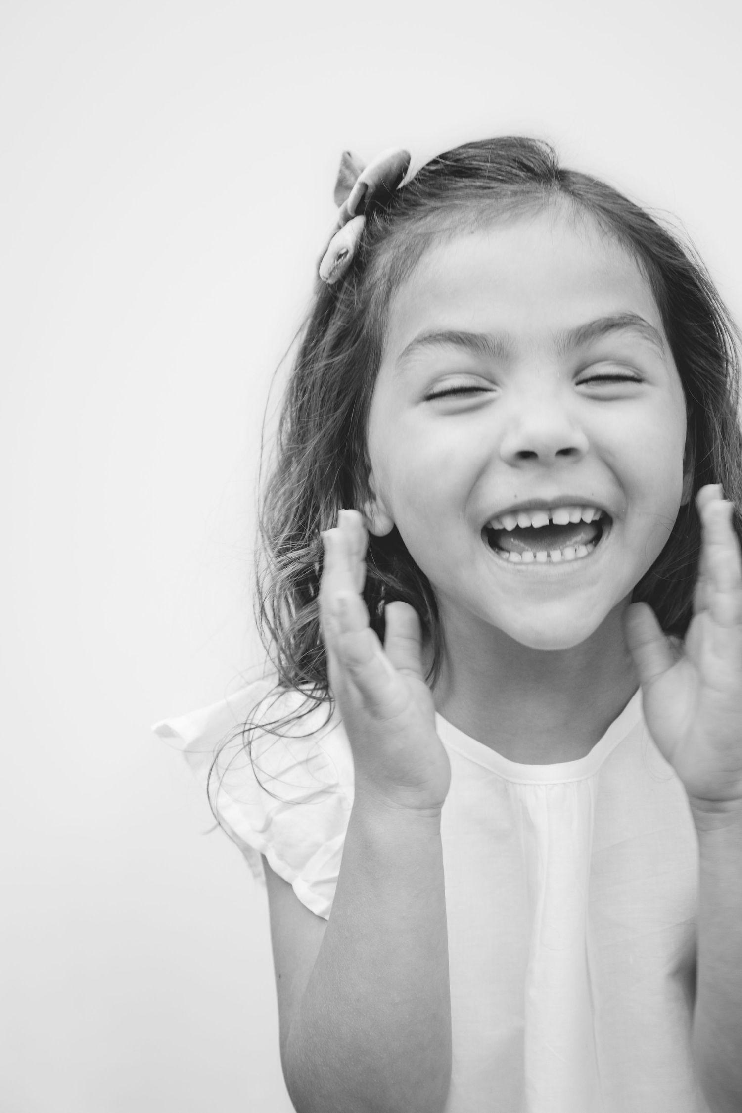 A sequence of four black and white photos showing a child's joyful expressions and laughter against a white background.