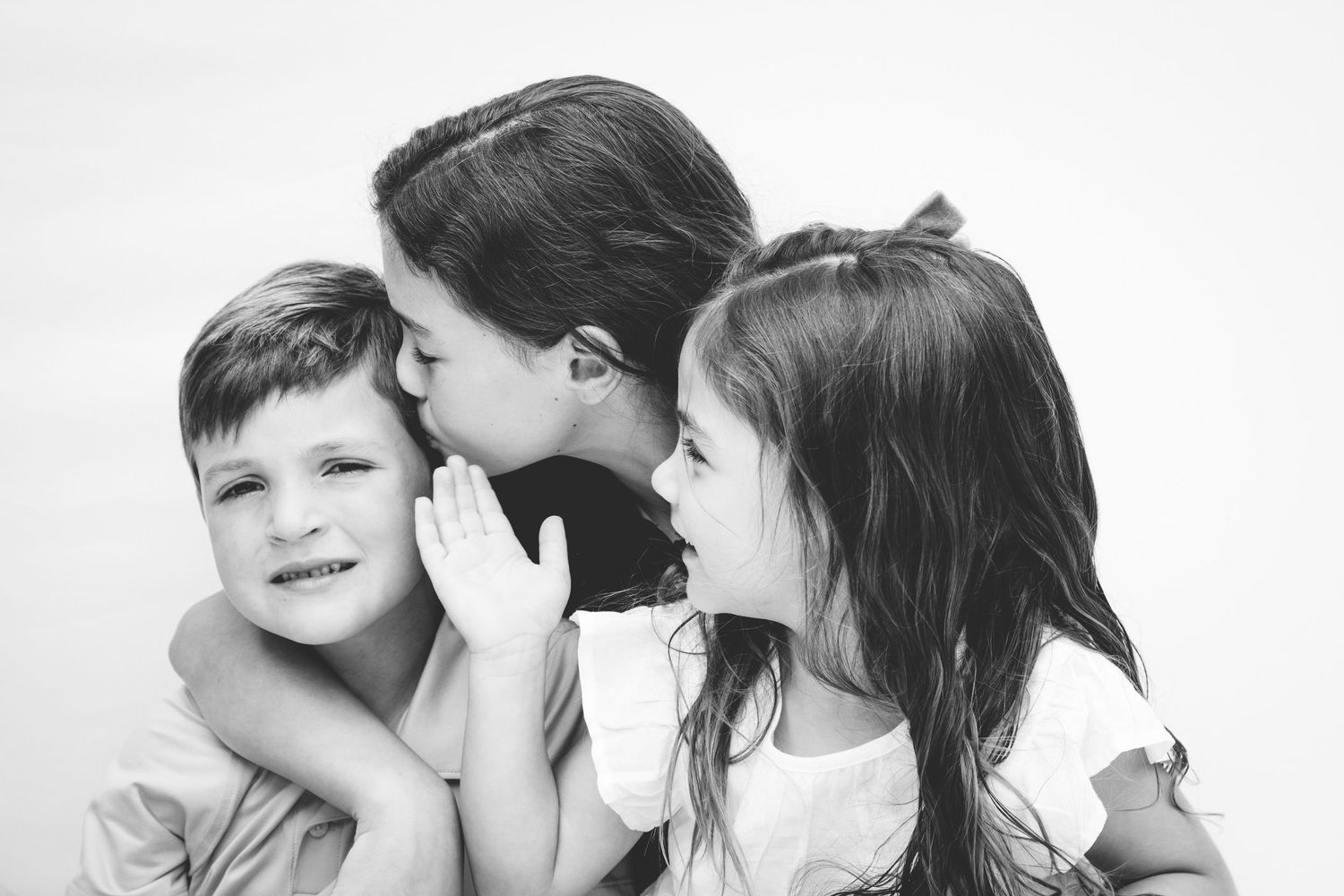 Four candid black and white photos show people whispering and sharing secrets with each other.