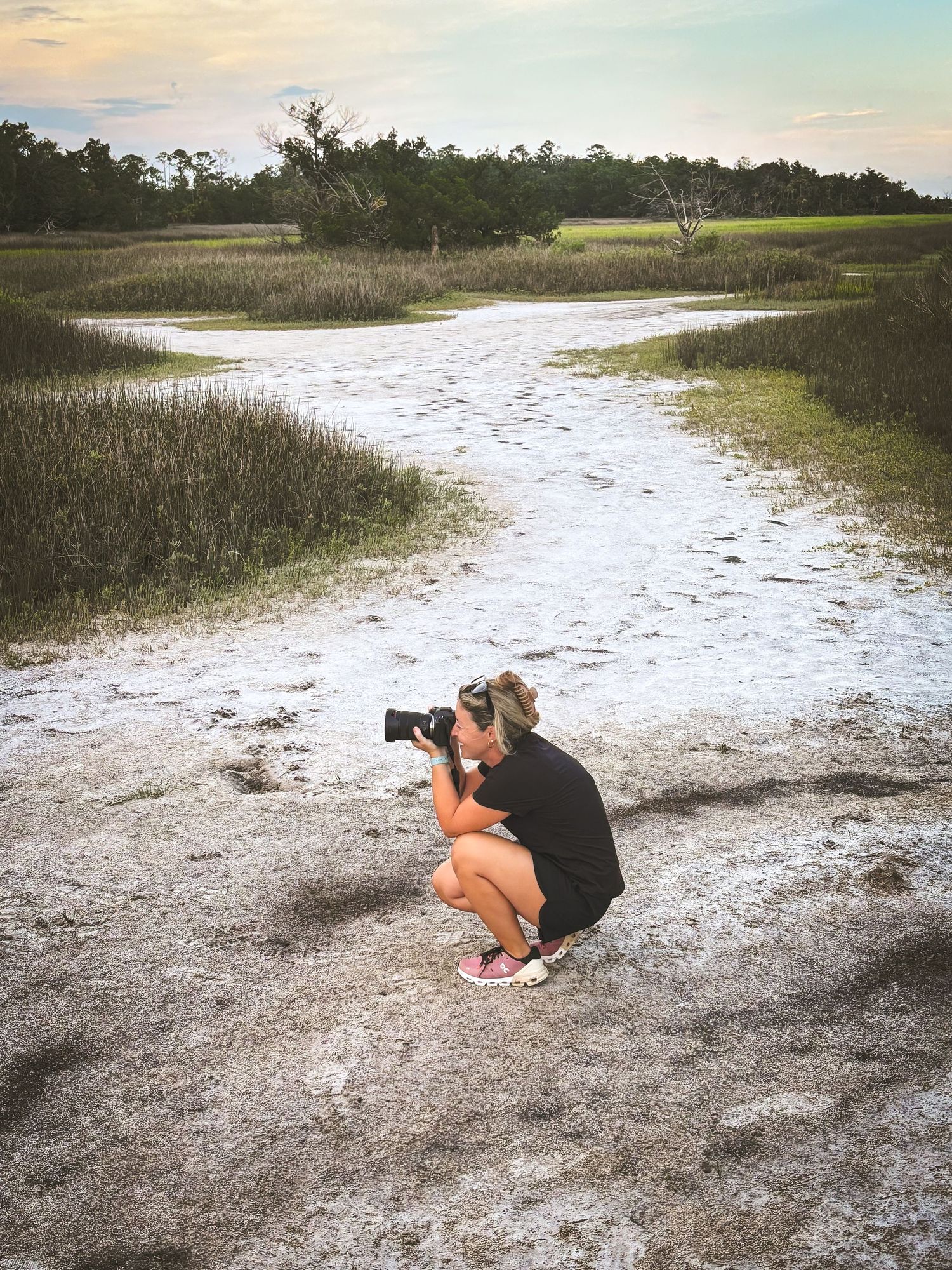 A sequence of photos showing someone crouched down taking photographs in a sandy coastal marsh landscape at sunset.