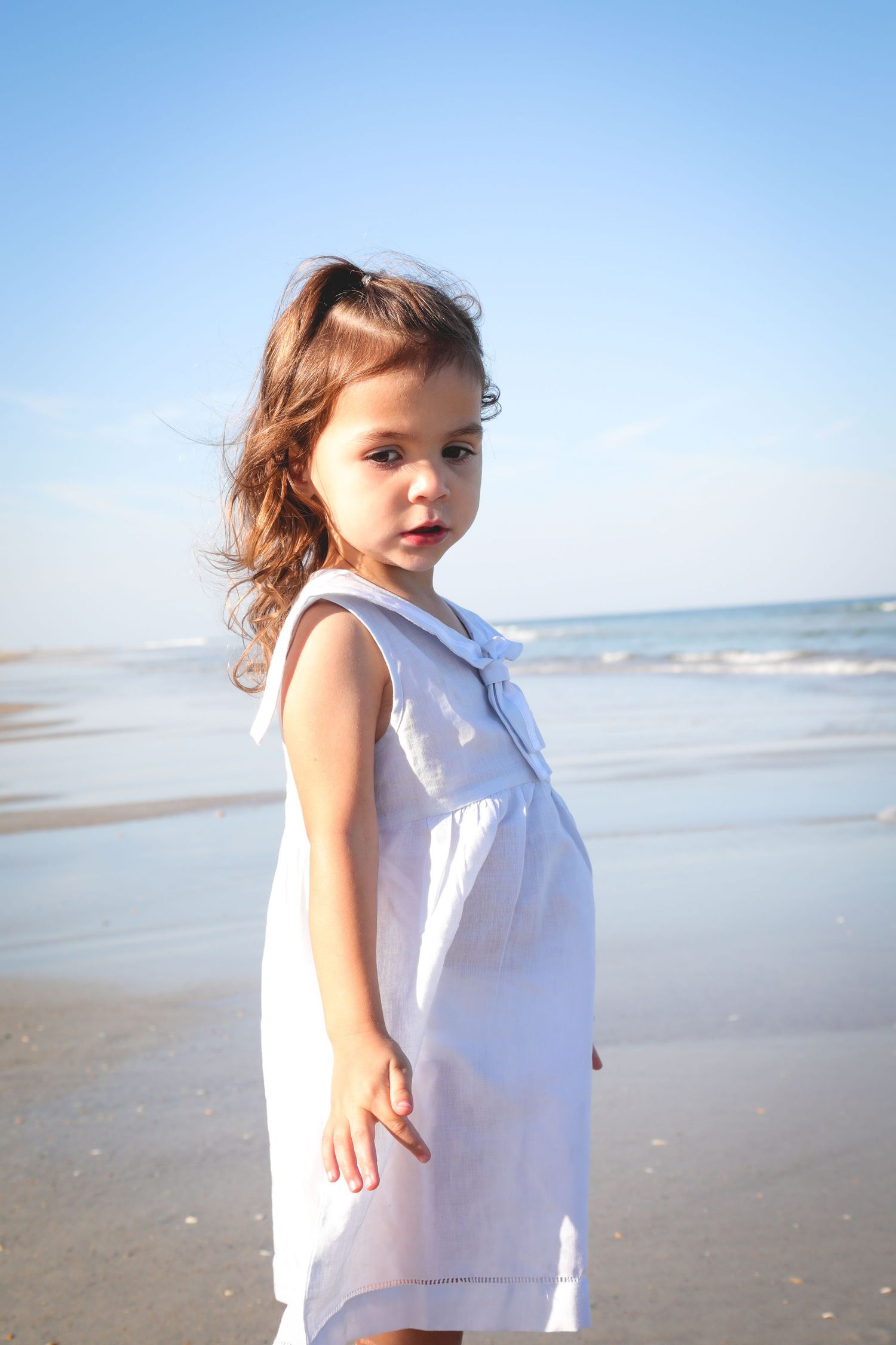 A grid of photos shows someone in a white sleeveless top posing on a sunny beach with ocean in the background.