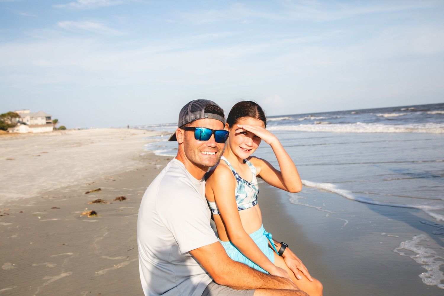 A couple sitting together at the beach during a sunny day.
