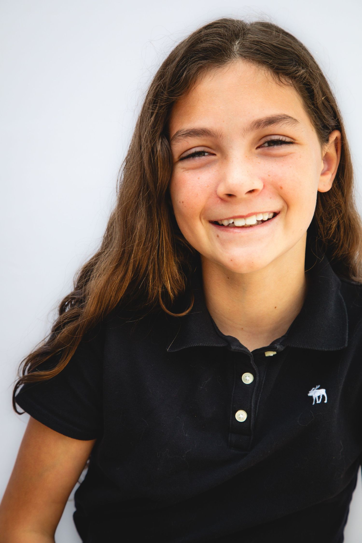 A series of four photos showing smiling expressions wearing a black polo shirt in front of a white background.