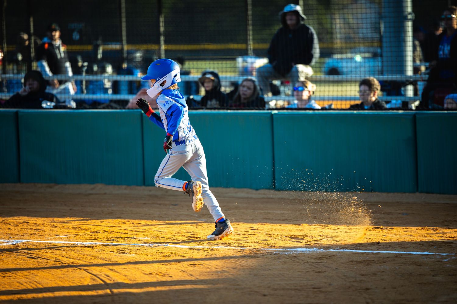 Baseball player in blue uniform slides into base during competitive game at stadium.
