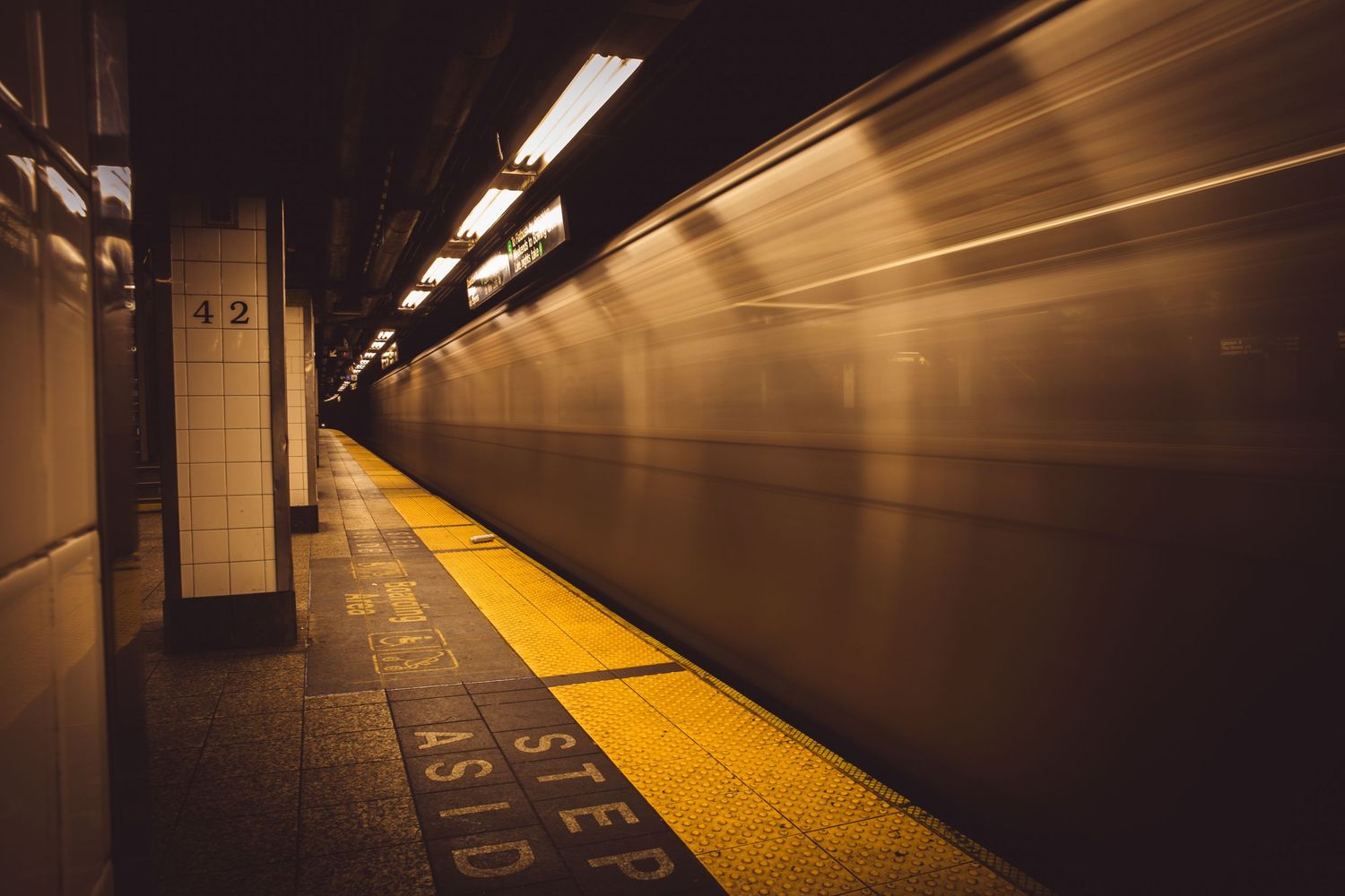 A dark subway platform with yellow safety strip and motion-blurred walls creating a dramatic tunnel perspective.