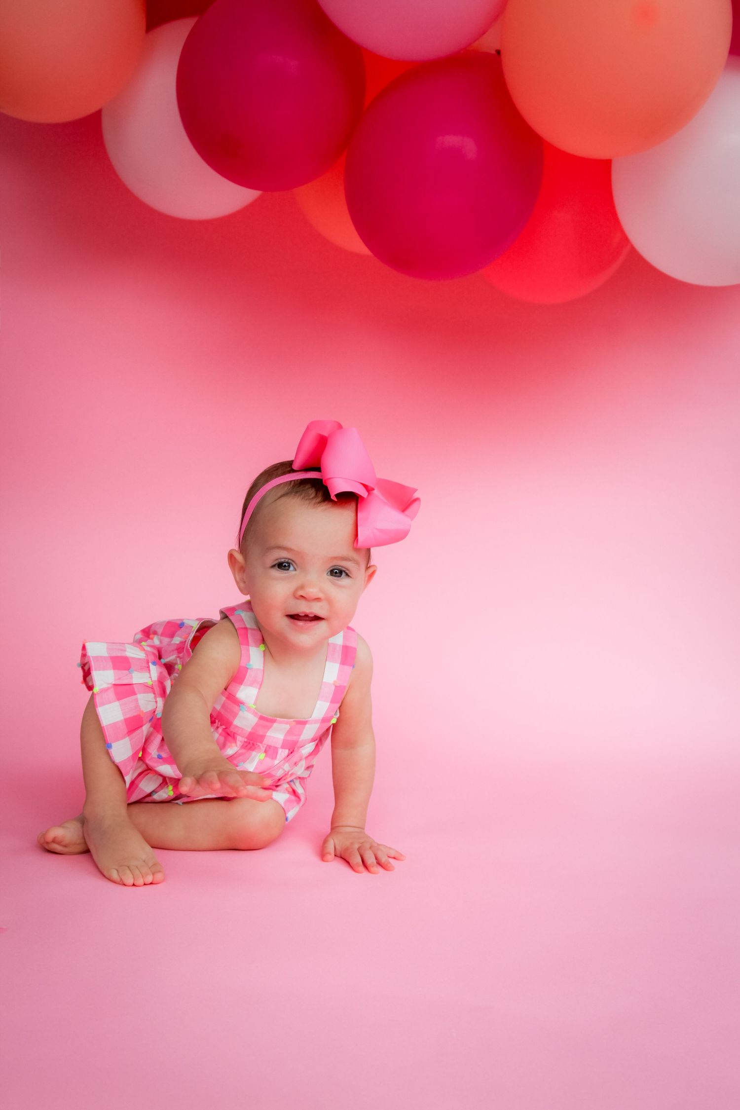 Pink and white balloons decorate a studio backdrop with a pink theme for a special photo session.