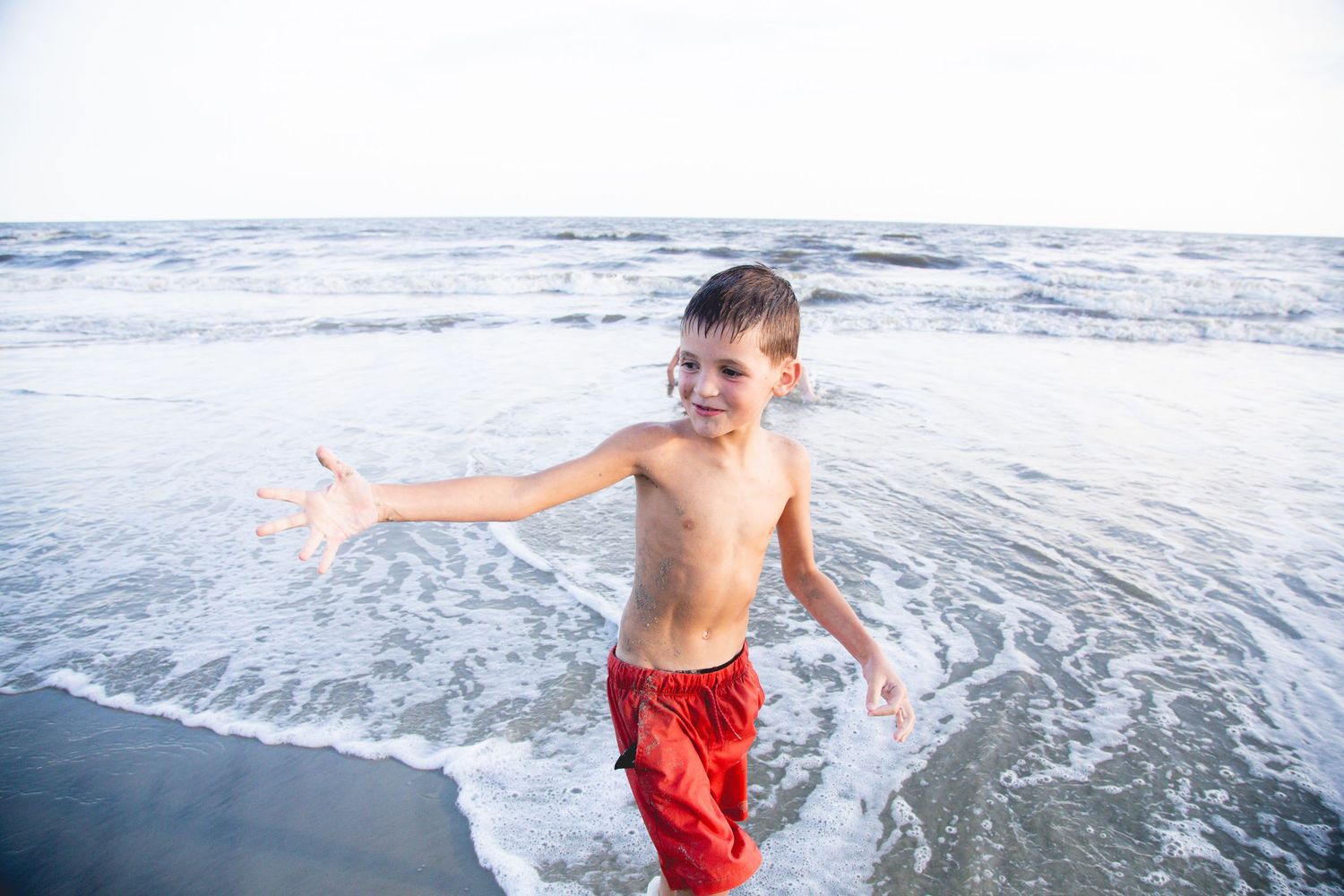 Child playing and splashing in the ocean waves on a sunny day.