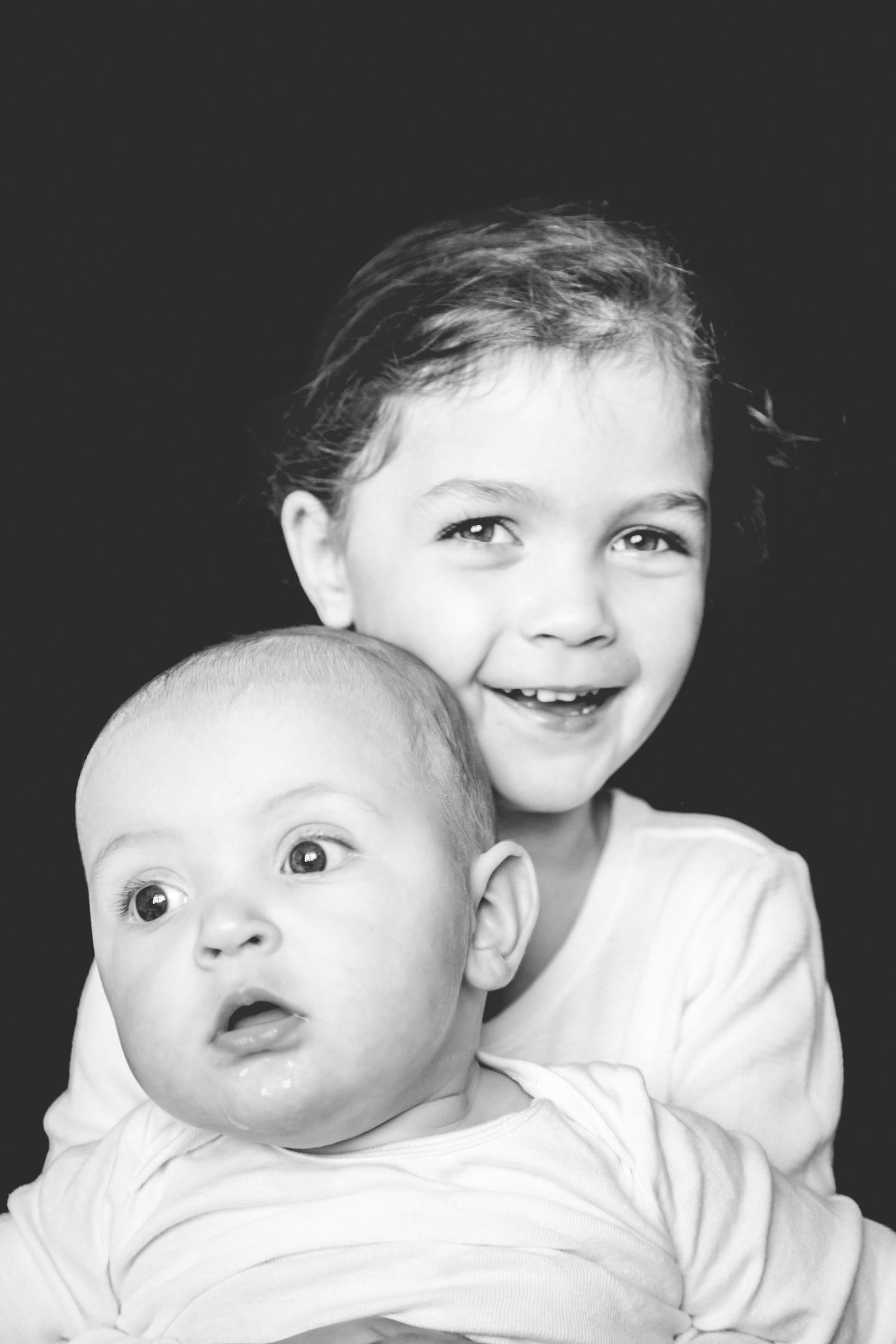 A collage of black and white close-up portrait shots showing different facial expressions and angles of a small baby.