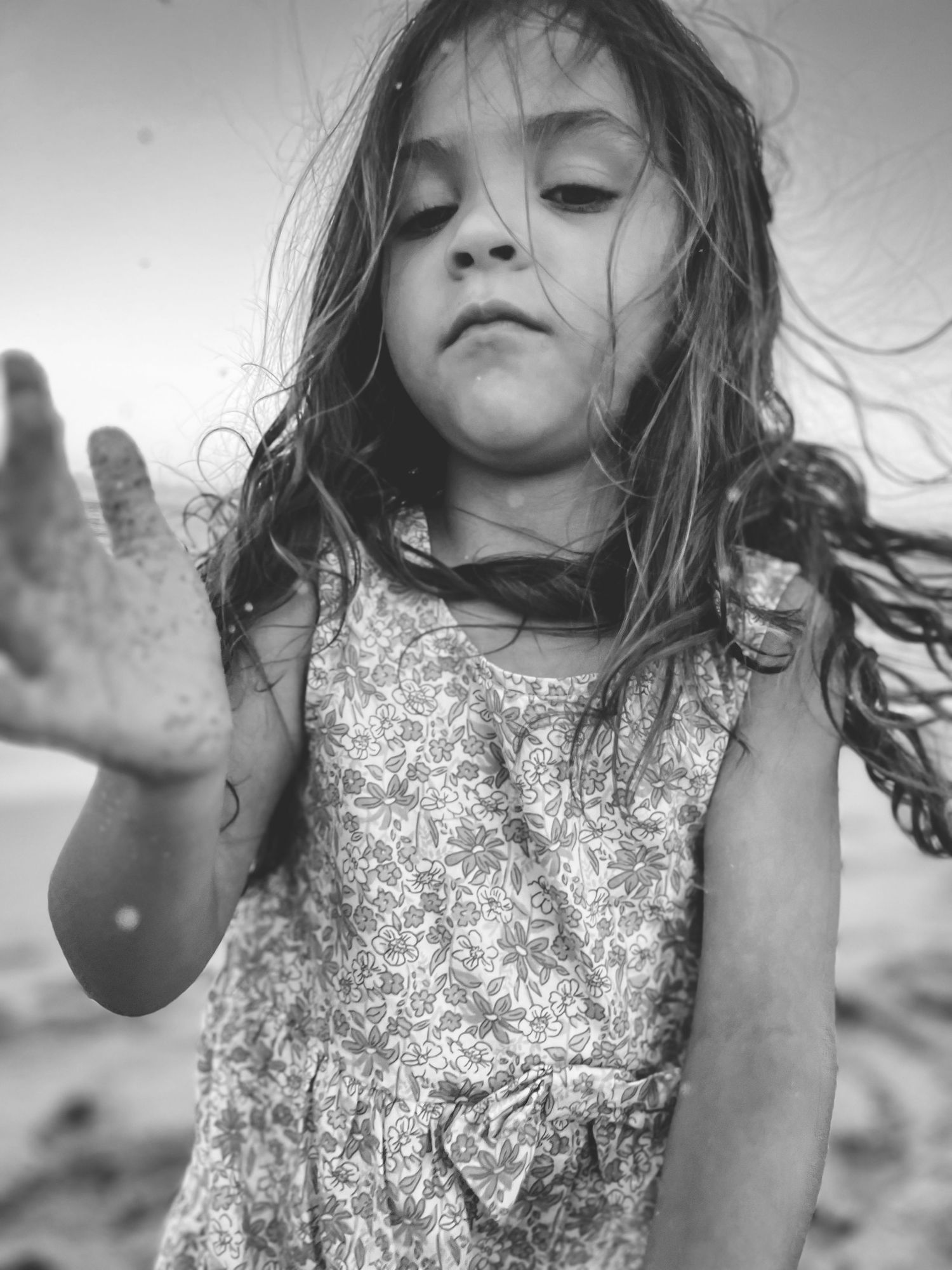 A black and white sequence shows a young child in a sparkly dress with windswept hair against a light background.