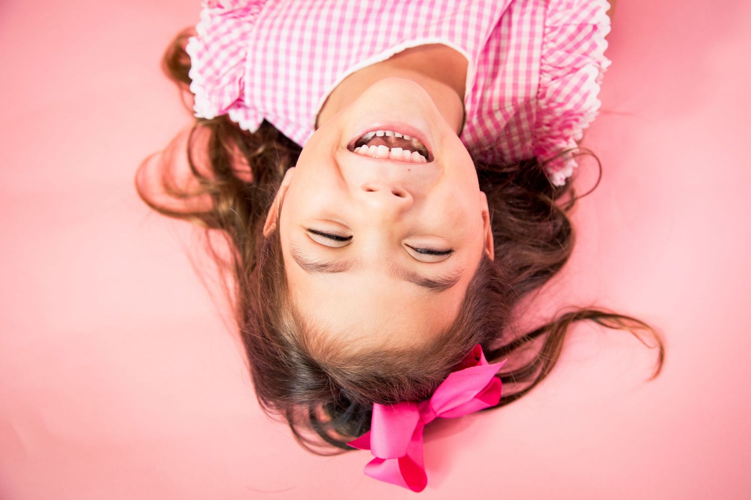 A spirited portrait series showing someone in pink and white gingham against a rosy background in varying poses.