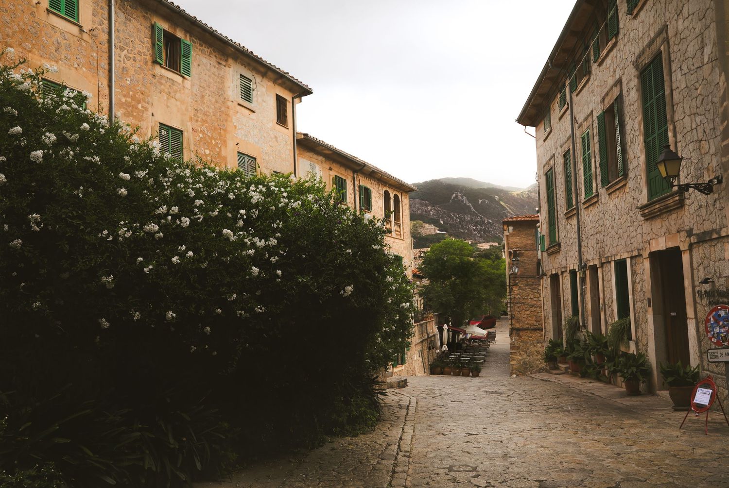 Ancient stone buildings line a narrow cobblestone street in a traditional Mediterranean village.