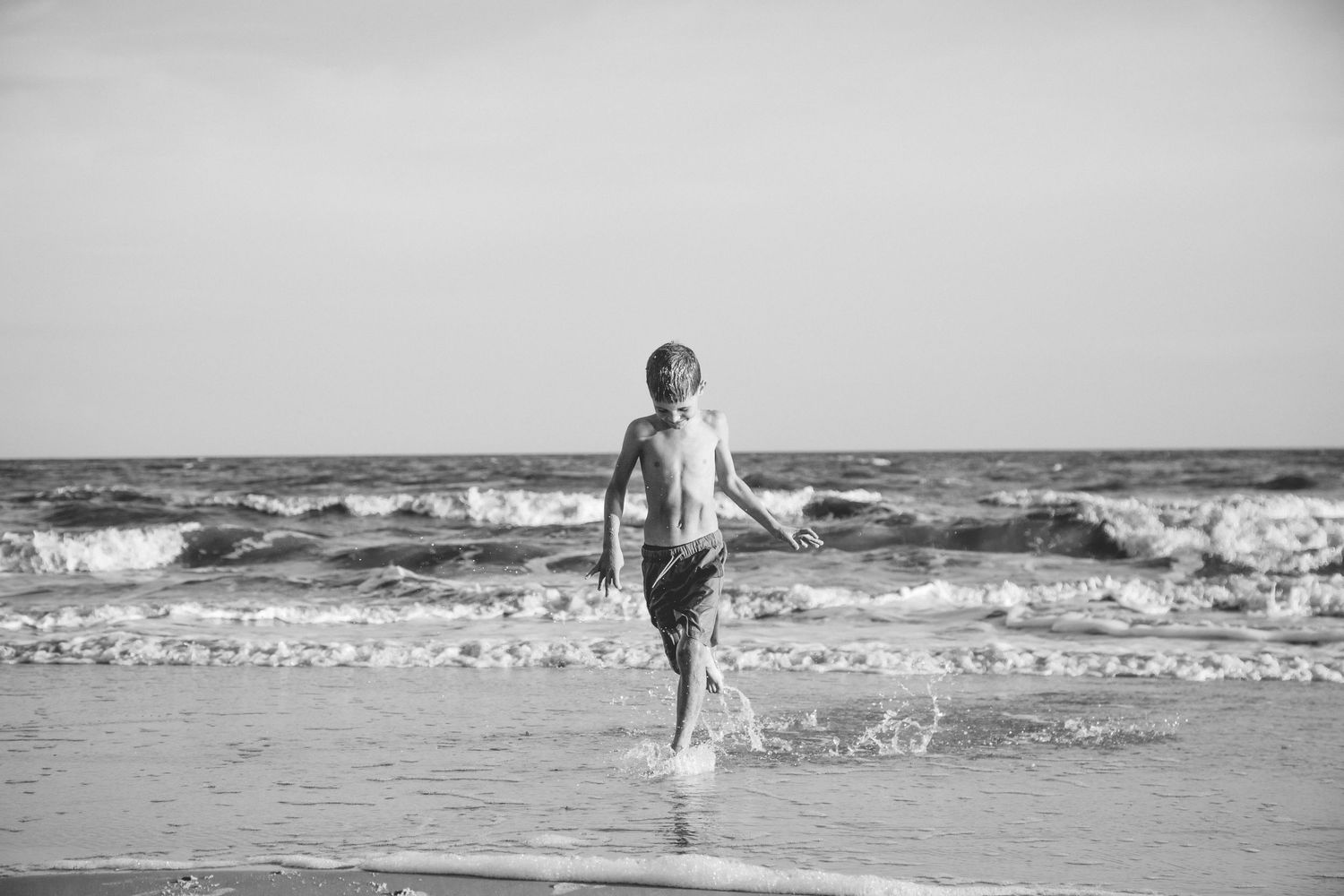 A black and white photo of a child playing in the ocean waves.