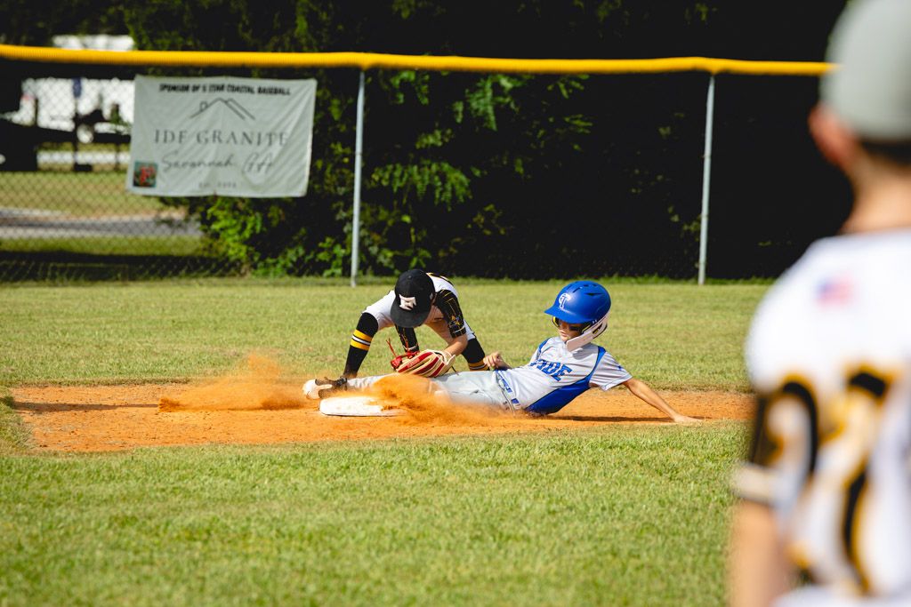 Baseball player diving to catch a ball on a sunny day at a baseball field.