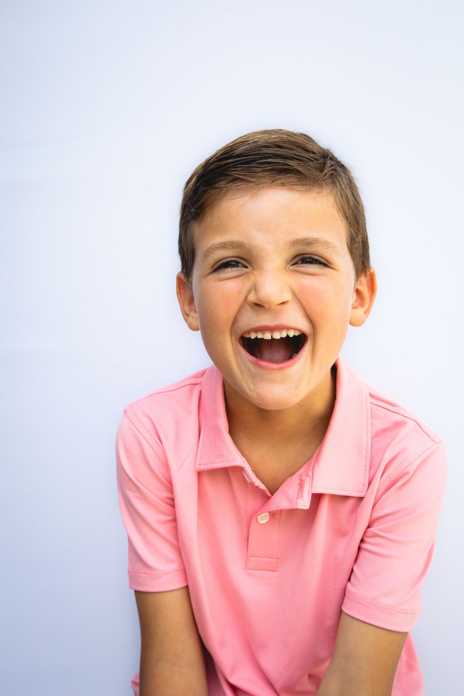 A laughing child wearing a pink polo shirt is shown in four sequential poses against a light background.