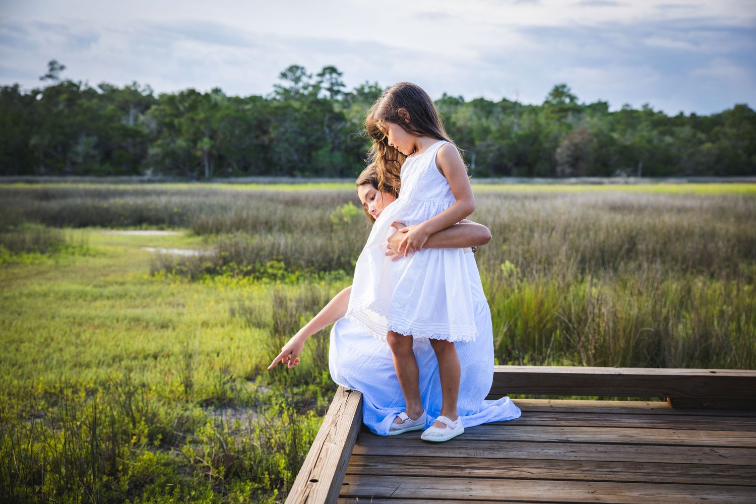 Series of scenic waterfront boardwalk photos with white dress against marsh and water landscapes at sunset.