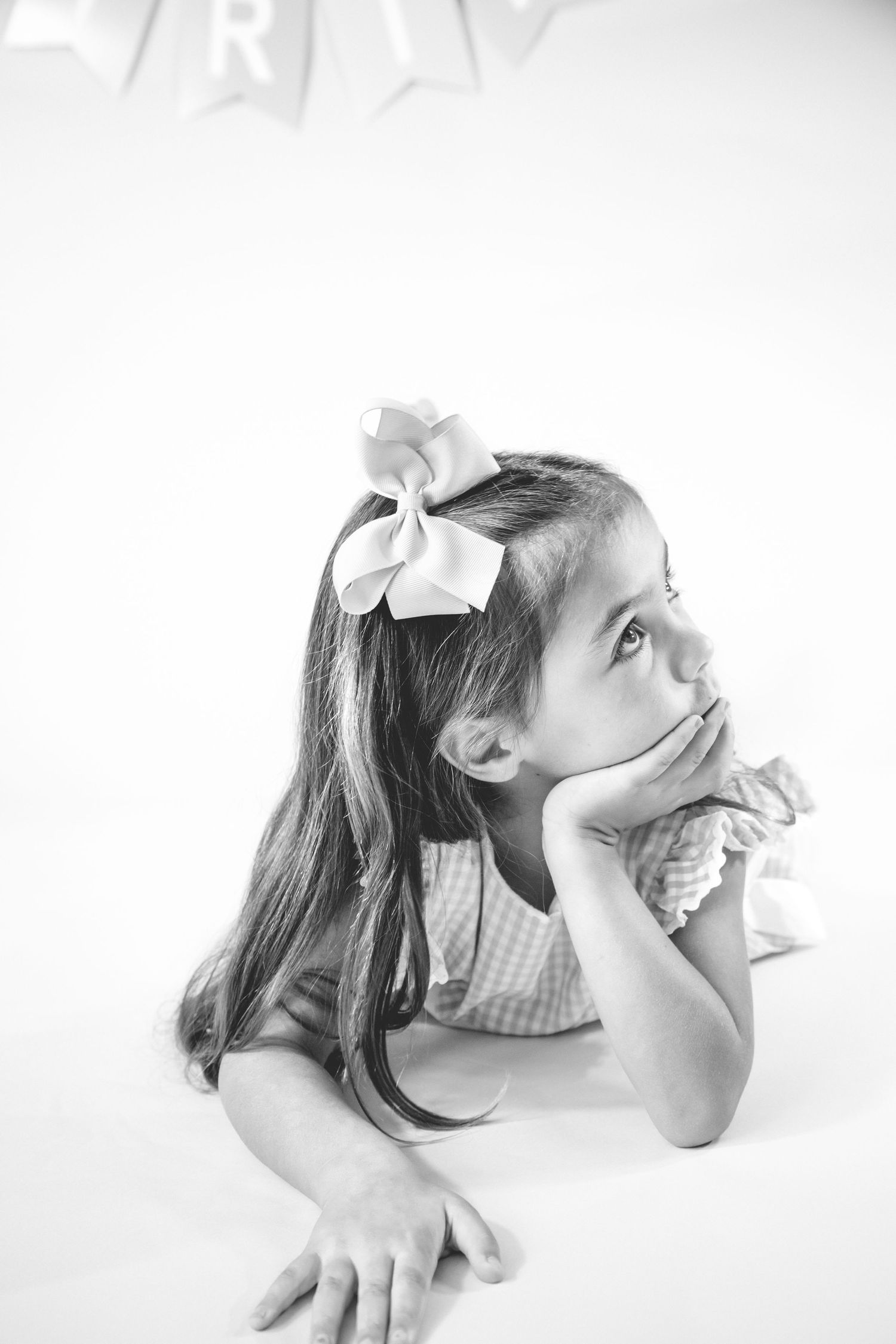 Four black and white artistic portraits of a figure with hair bows displaying playful expressions against white background.