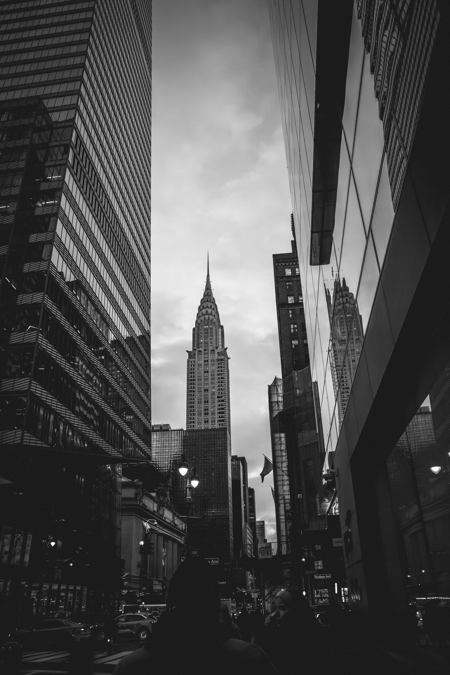Black and white view of the iconic Chrysler Building in New York City framed by modern skyscrapers on a moody day.