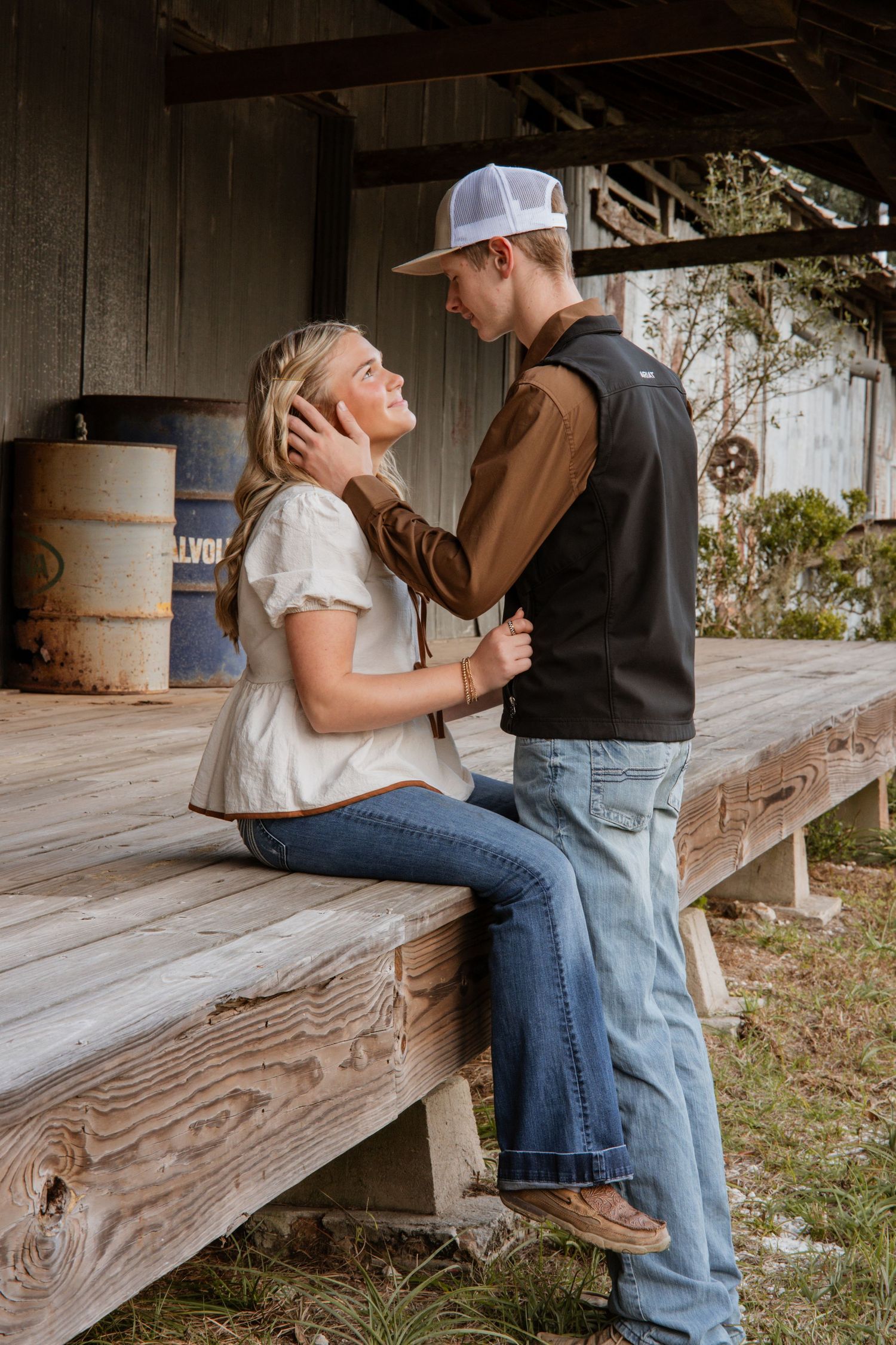 A romantic moment unfolds between two people sitting on wooden steps in a rustic outdoor setting.