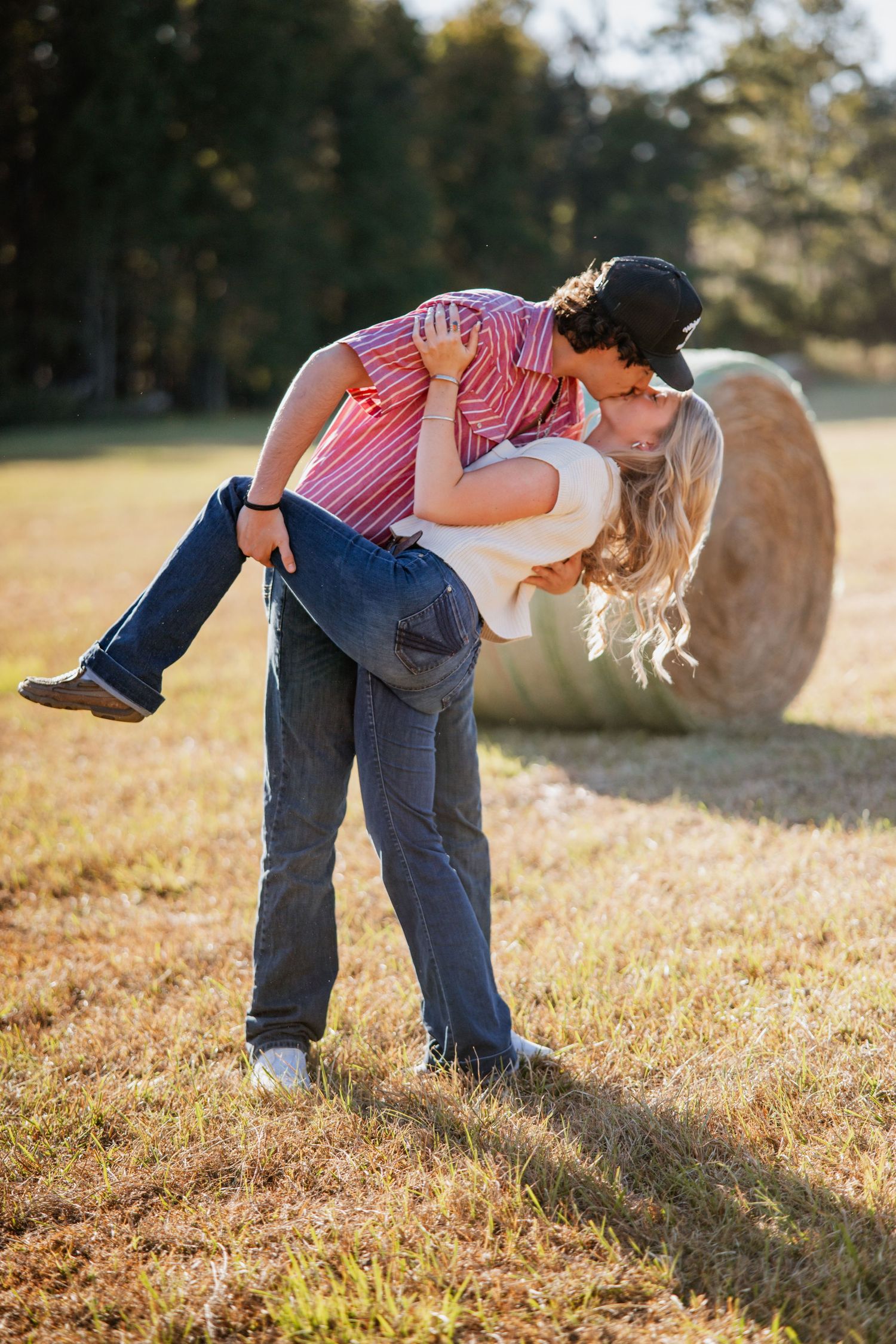 A playful couple dips and dances together in a sunlit autumn field.