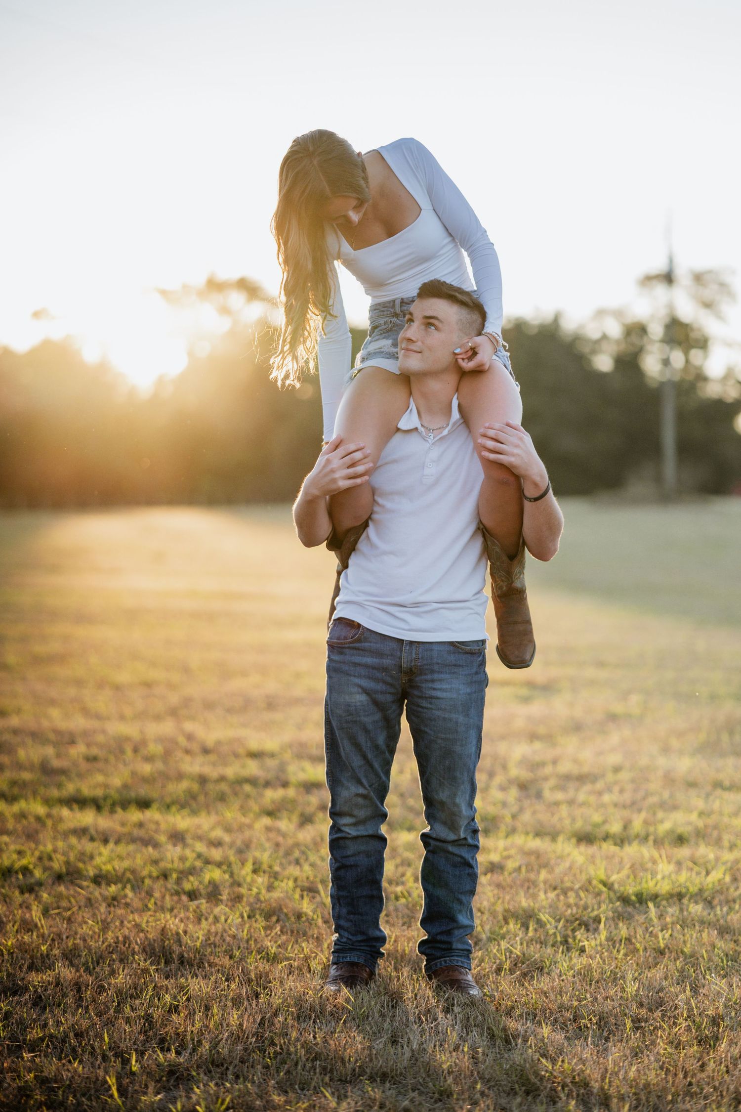 Playful piggyback ride in a golden field during sunset.