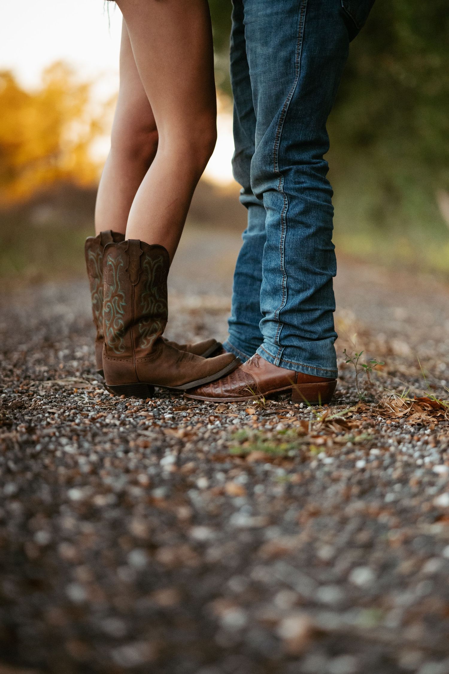 Close-up of boots and feet standing together on gravel path.