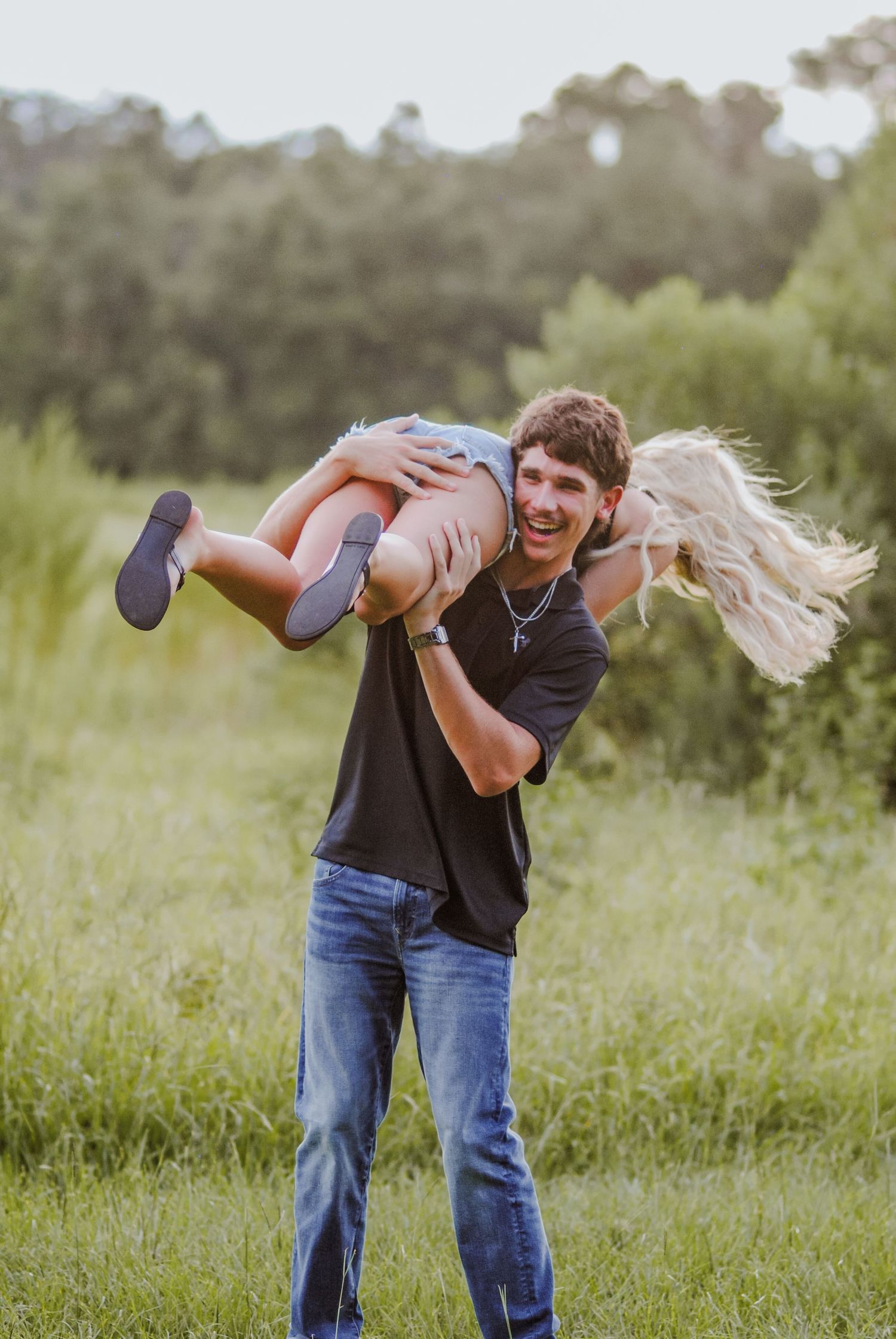 Couple performing dance lifts and spins in a grassy field during sunset.