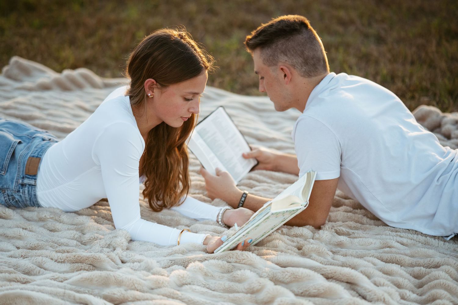 Couple lying together on a sandy beach during a romantic photoshoot.