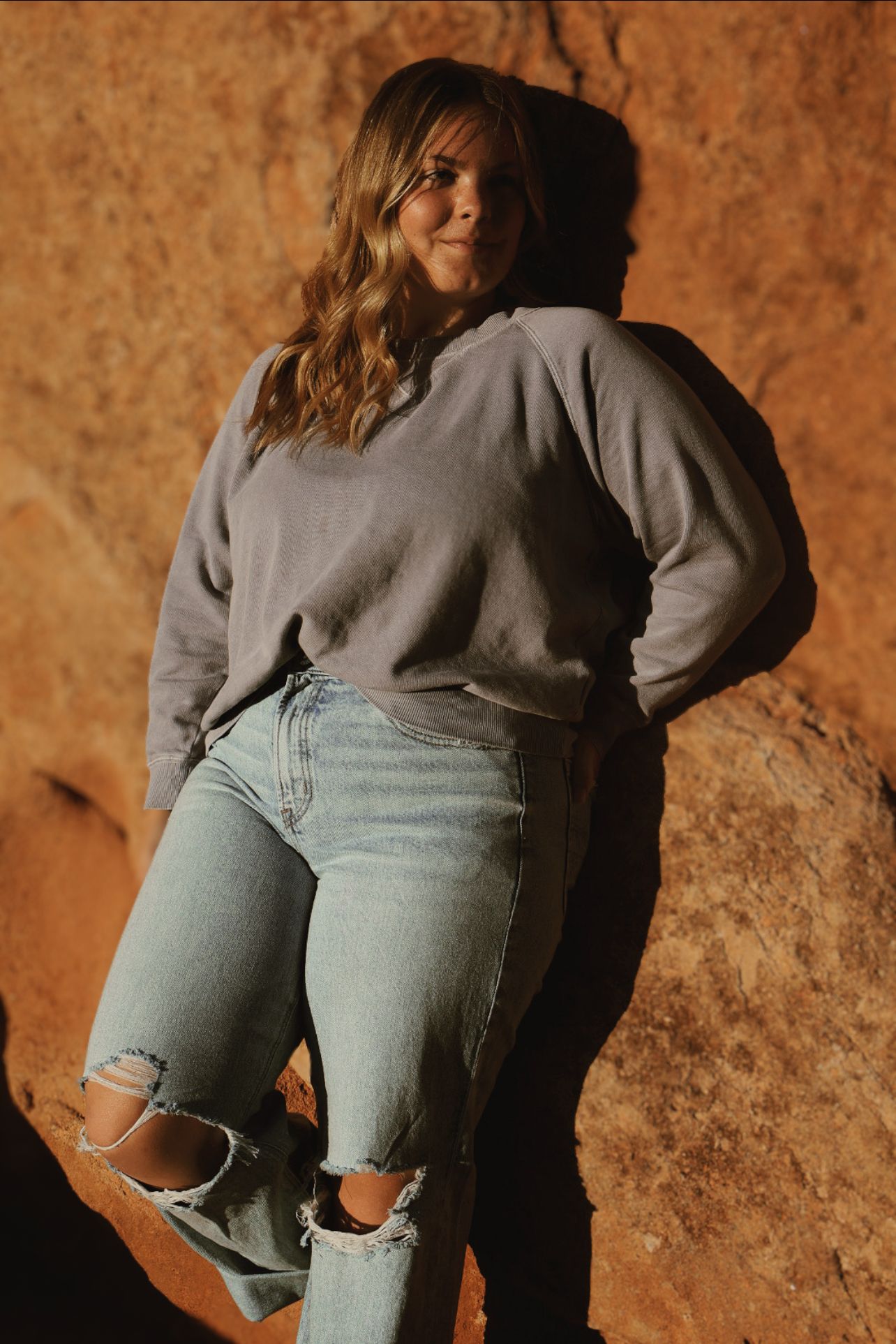 Female high school senior posing against warm red rocks during a senior photography session at Garden of the Gods in Colorado Springs, CO.