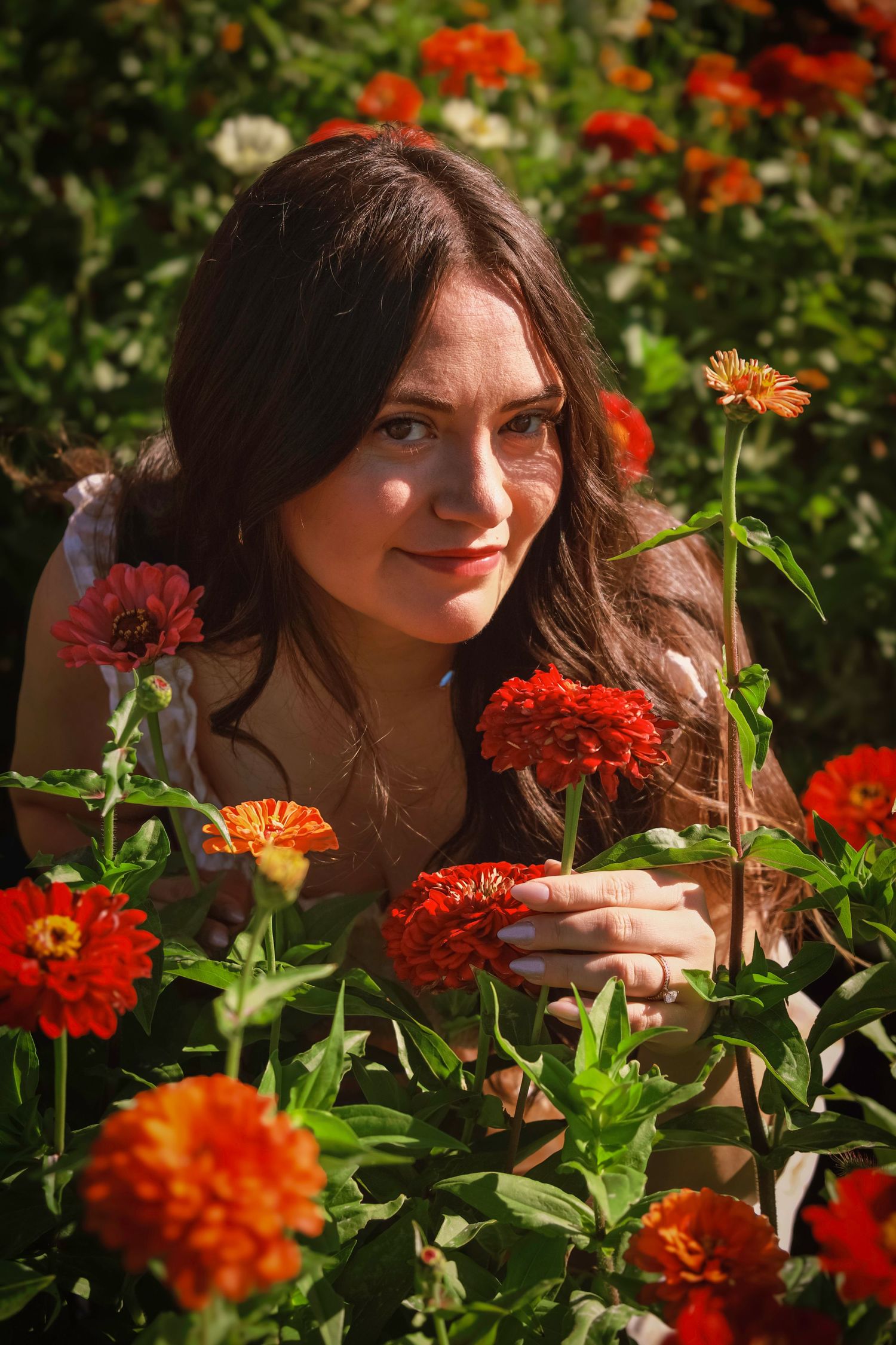 Natural portrait of a young woman surrounded by colorful blooms during a flower field photography session in Colorado.