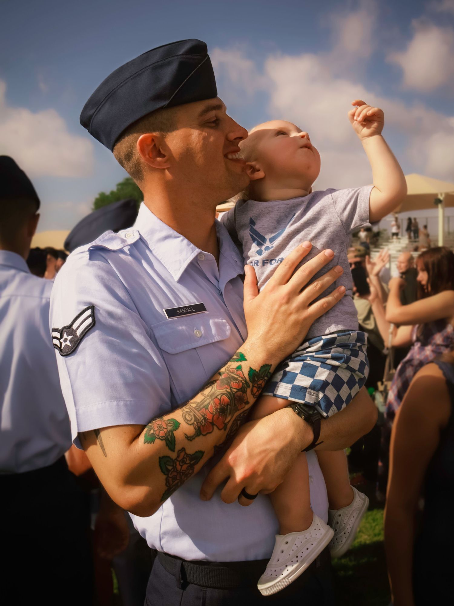 Airman holding and kissing his young child after graduation during a U.S. Air Force Academy graduation family photography session.