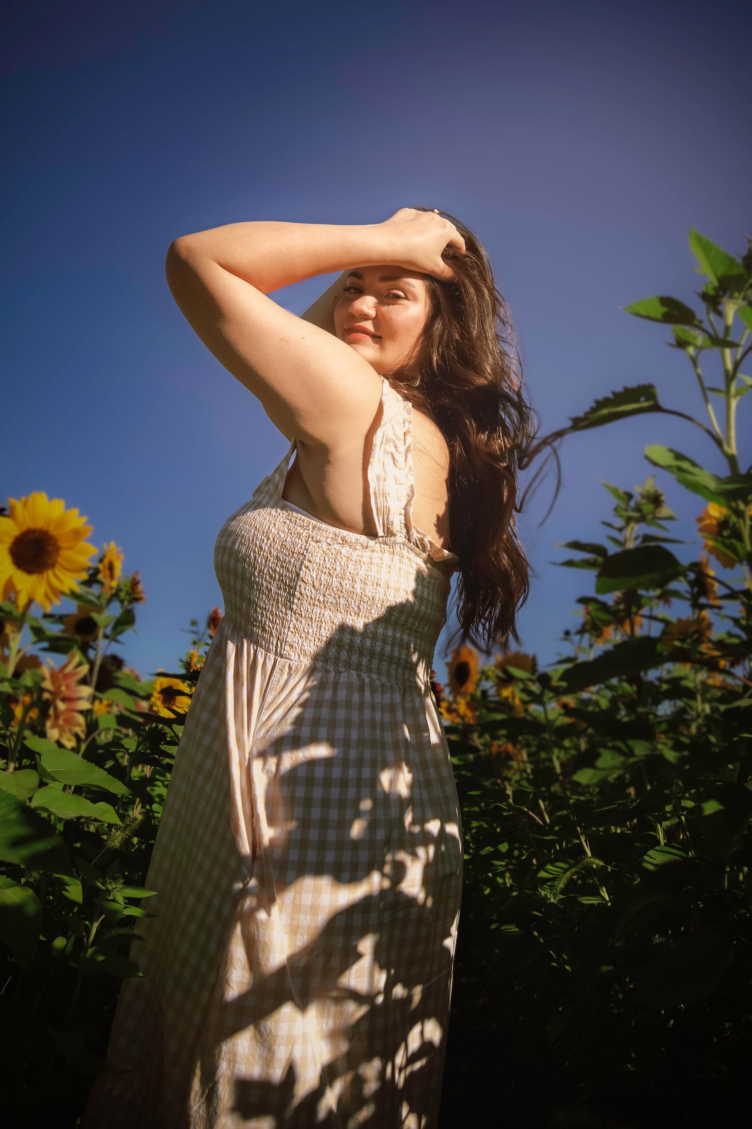 Artistic portrait of a young woman posing among sunflowers at Gather Mountain Blooms in Colorado.
