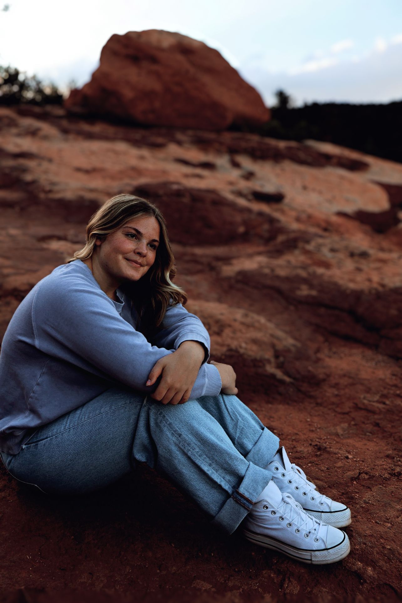 Female senior sitting on red rock formations during an outdoor senior portrait session at Garden of the Gods in Colorado Springs.