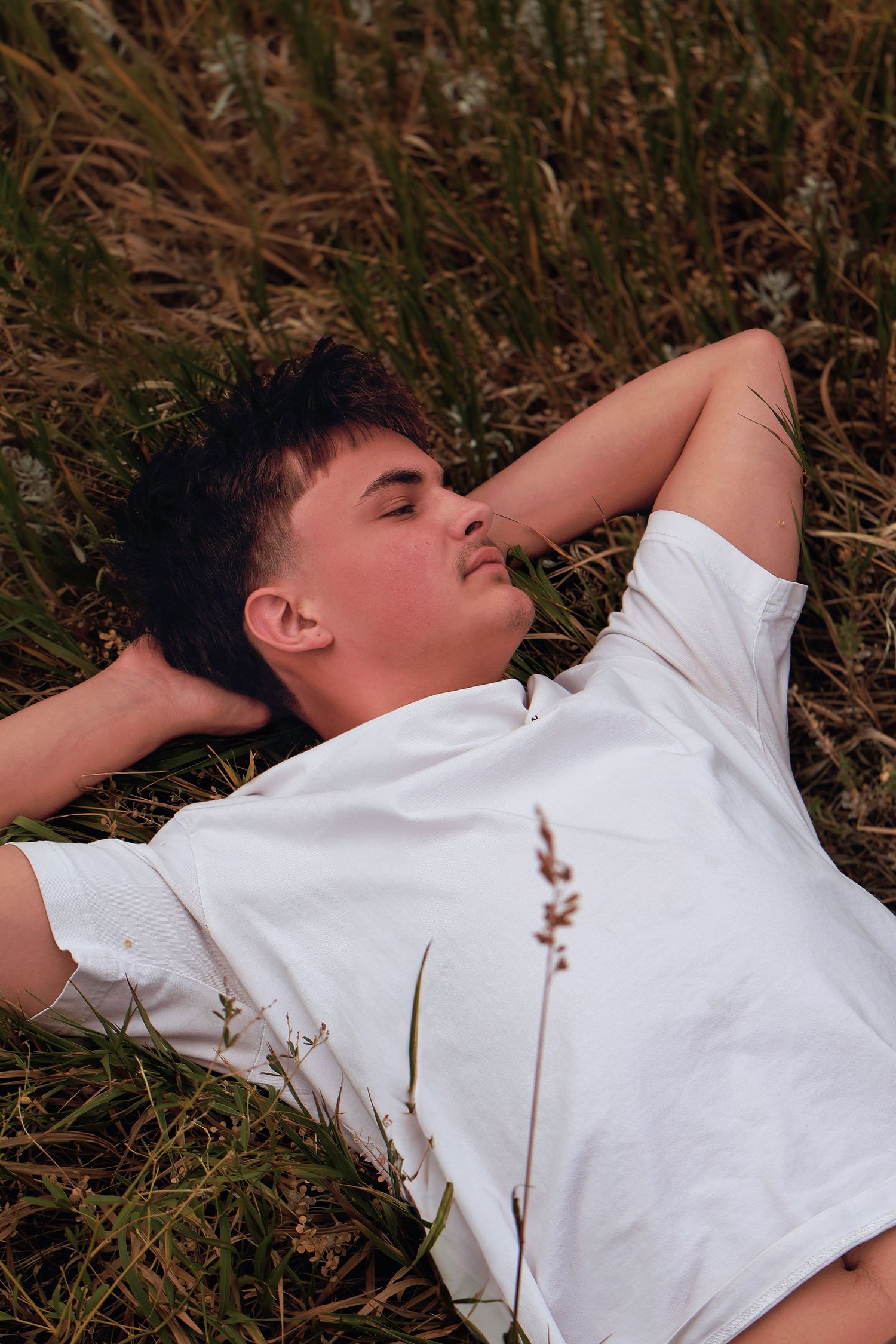 Male high school senior relaxing outdoors during a senior photography session at Red Rocks Park and Ampitheatre in Morrison, Colorado.