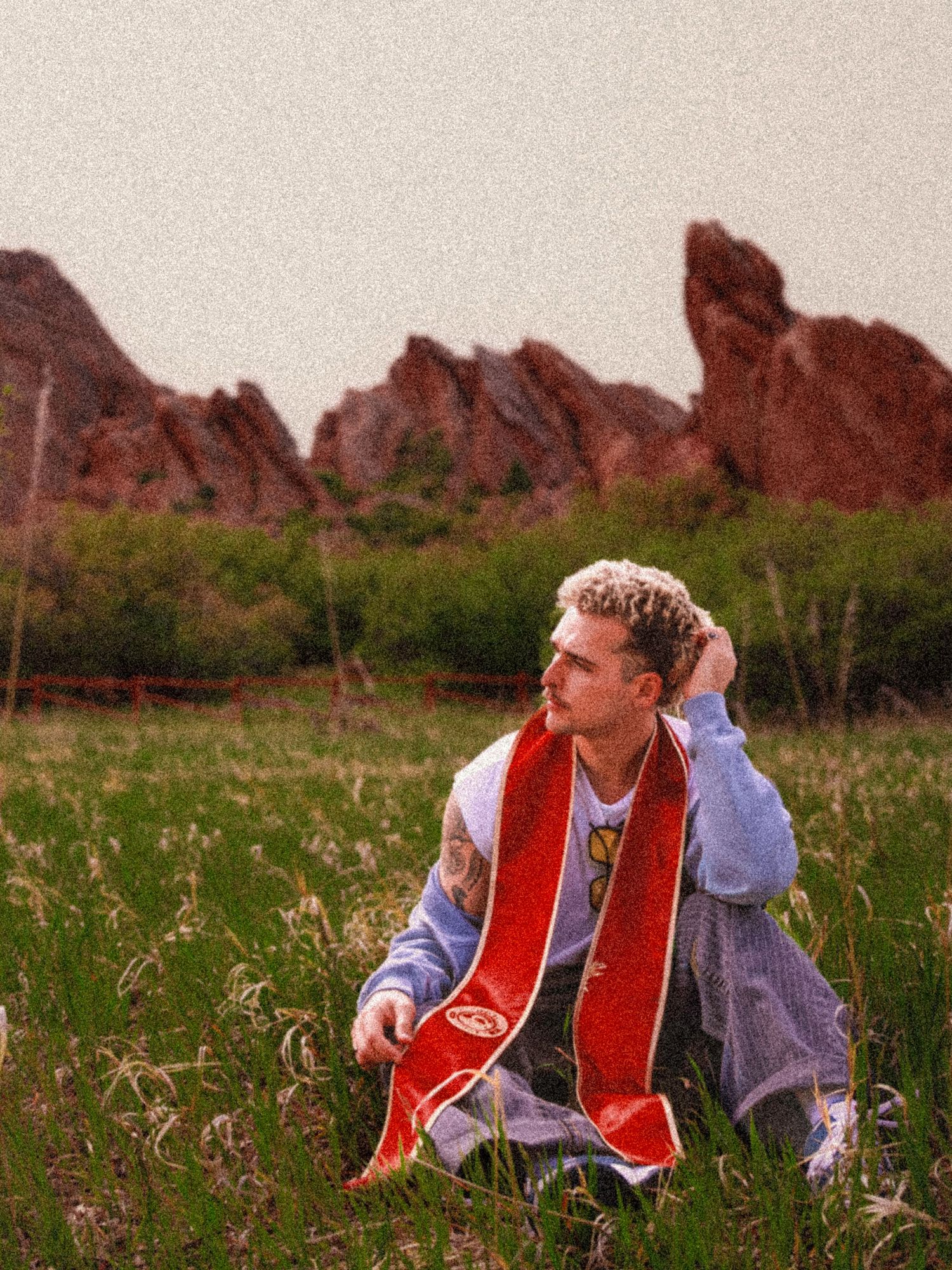 Seated in field
Colorado Springs senior photography portrait of a male graduate sitting in a grassy field near red rock formations.