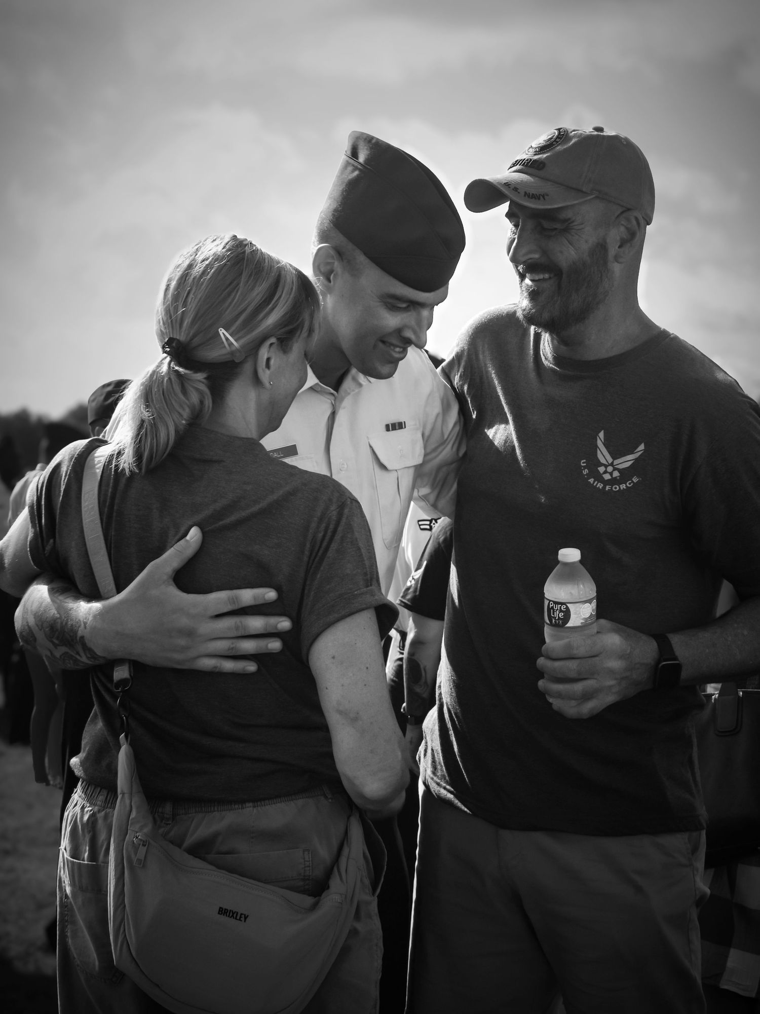 Black and white photo of an Airman embracing family after graduation at the U.S. Air Force Academy in Colorado Springs.
