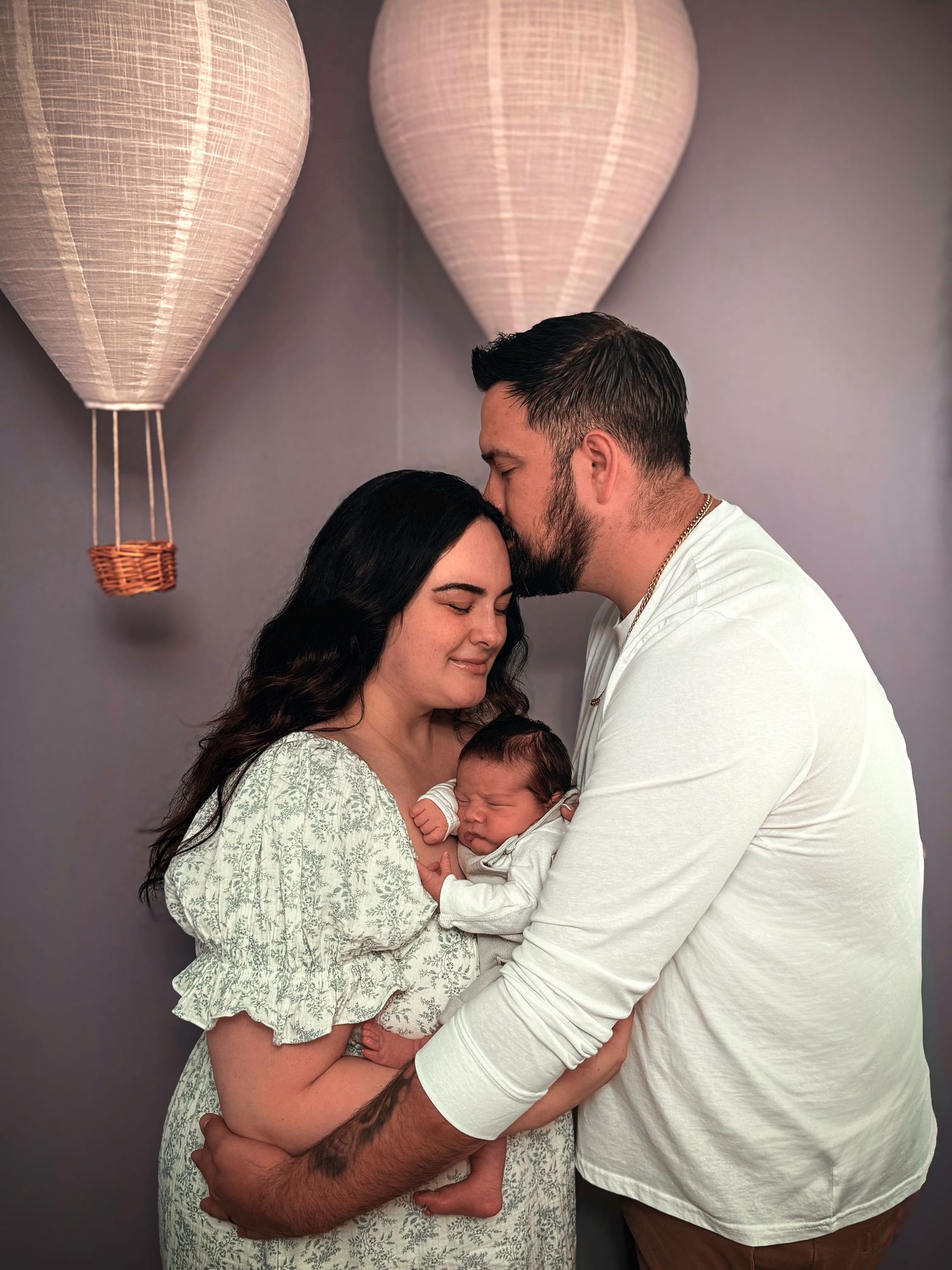 New parents cuddling their newborn baby during an intimate in-home family photography session in Colorado Springs.