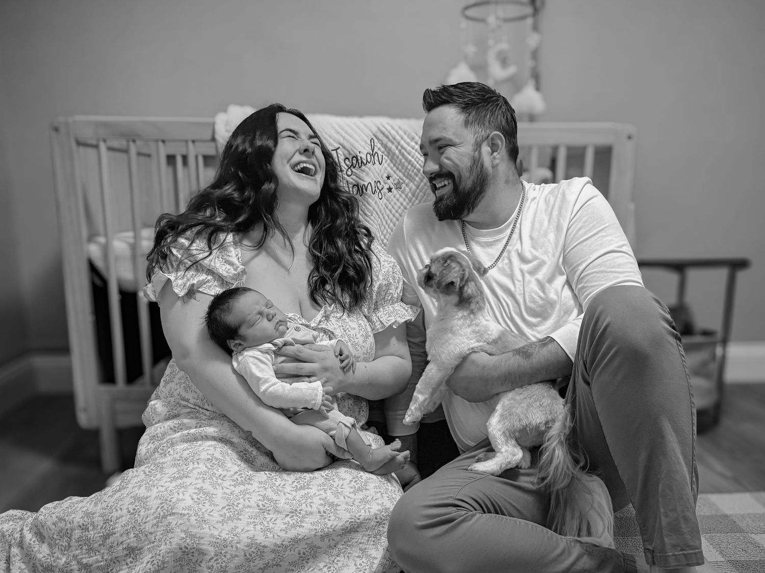 Parents laughing together while holding their newborn baby during a relaxed in-home family photography session in Colorado Springs.