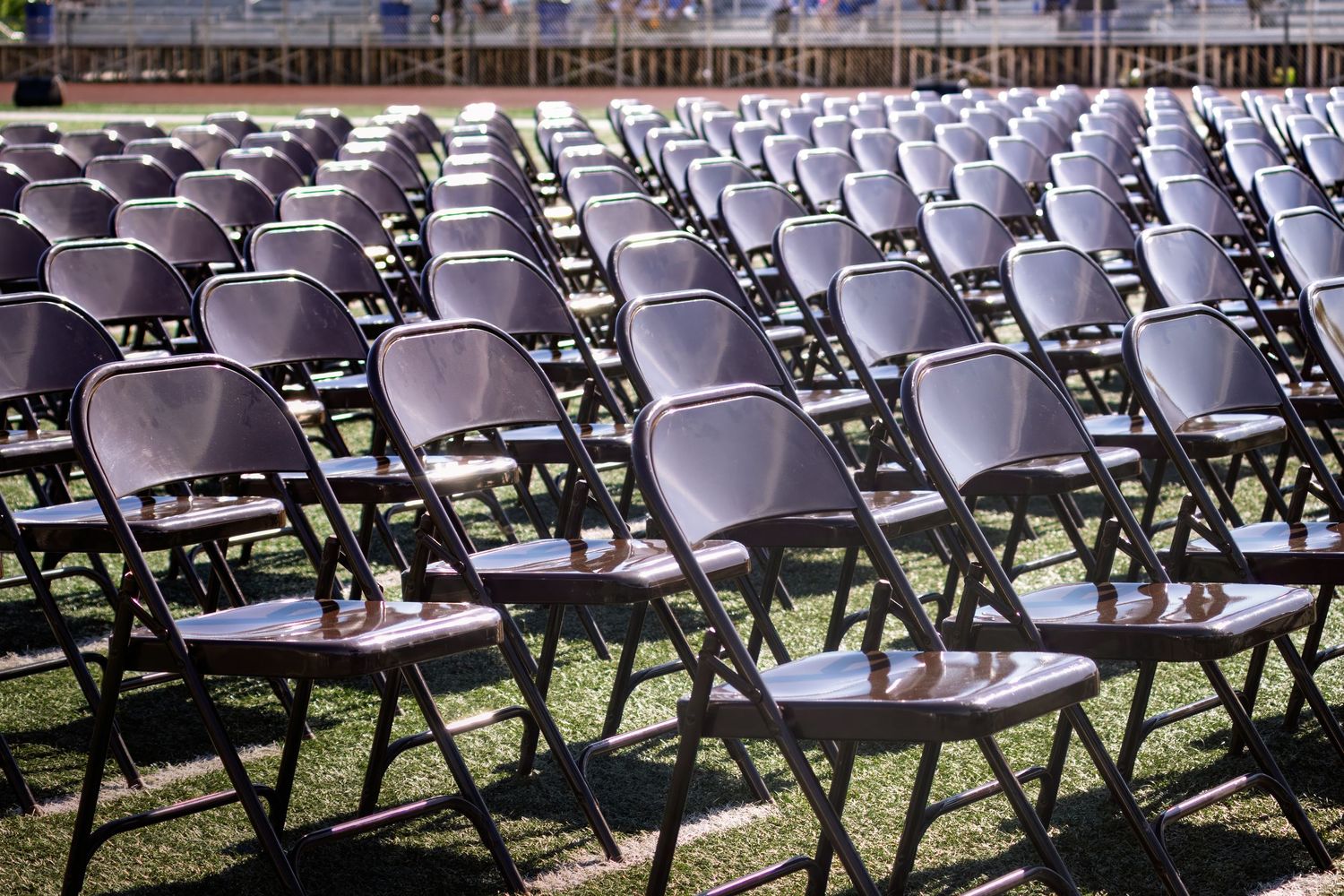 Empty rows of folding chairs are arranged at a graduation ceremony venue, waiting for guests to arrive.
