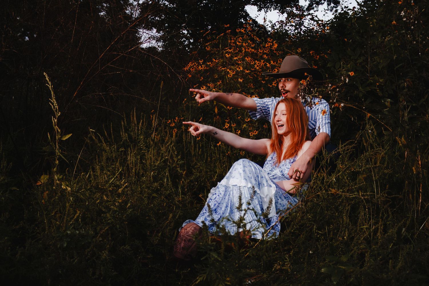 Person in white dress points while standing in tall grass during golden hour lighting.