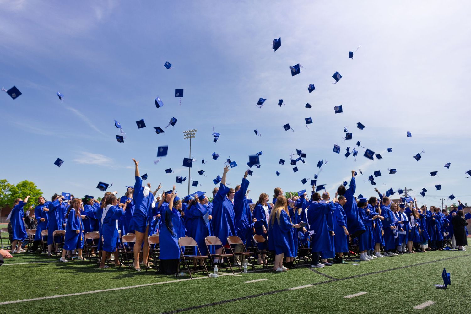 A sequence of photos showing graduates in blue caps and gowns tossing their mortarboards into the air during graduation.