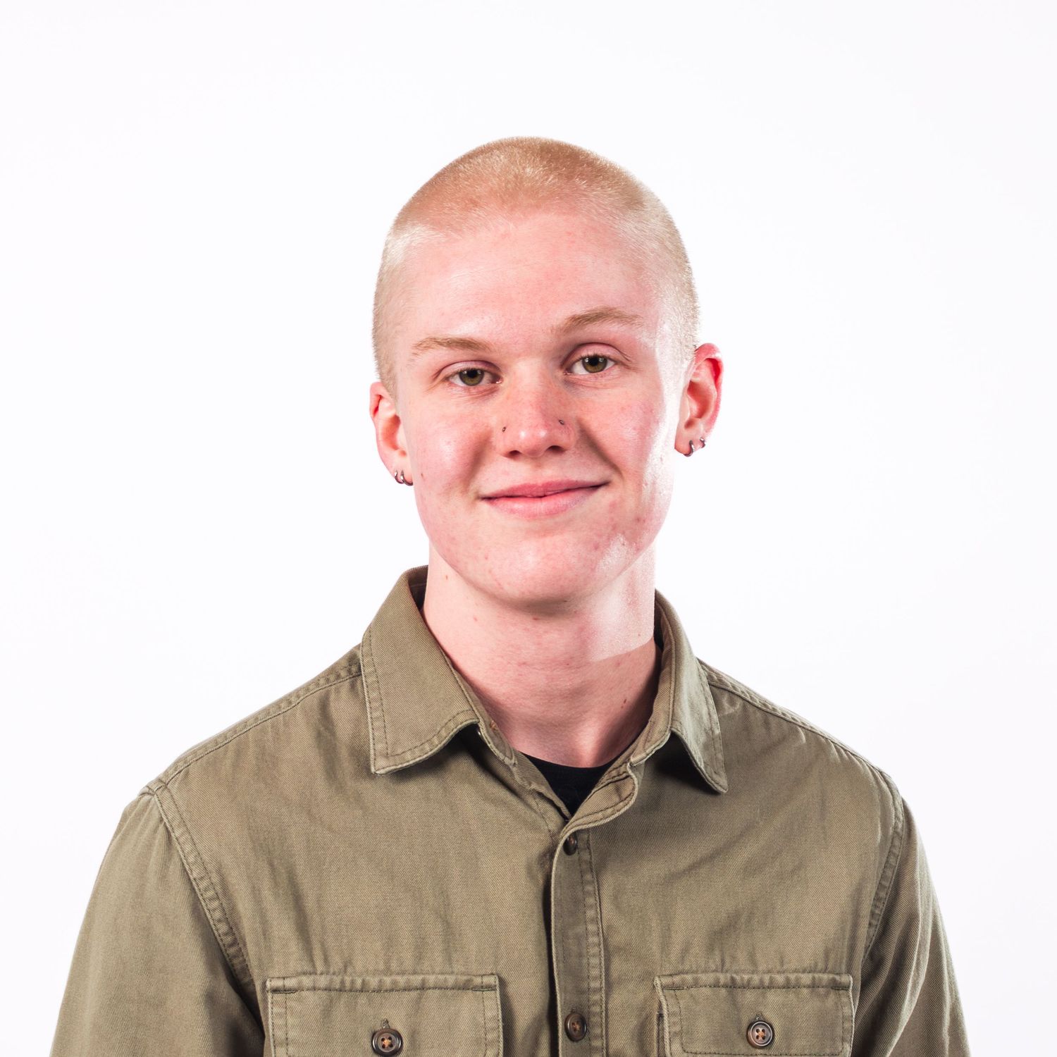 Young man with short blonde hair wearing an olive green button-up shirt, smiling against a white background.
