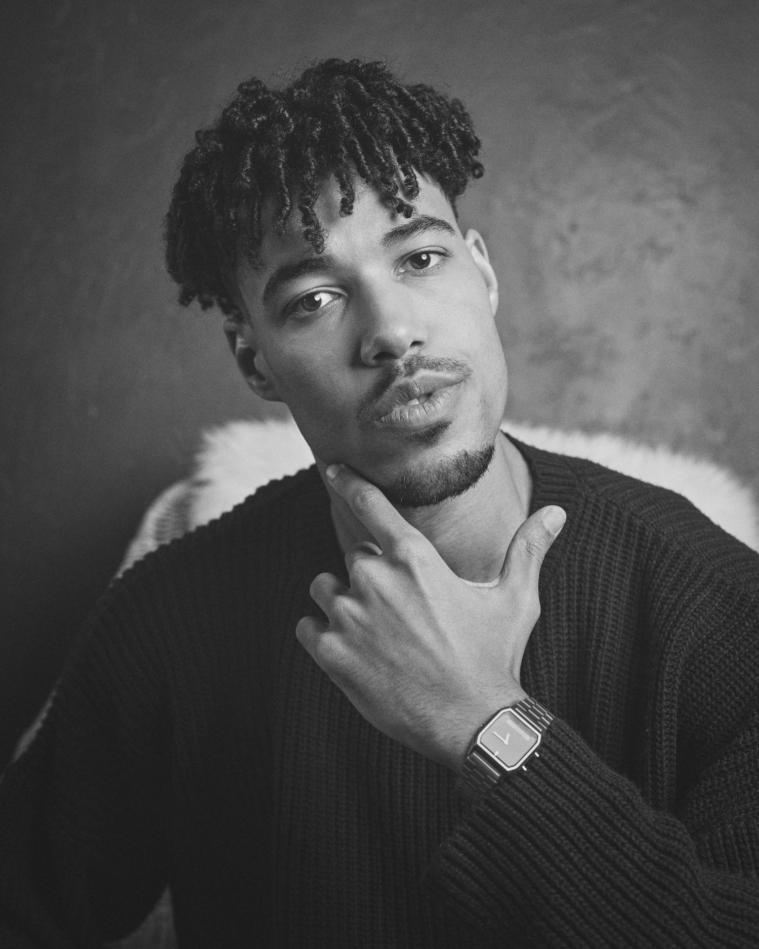 A black and white portrait series showing a person in a dark sweater posing thoughtfully against a textured background.