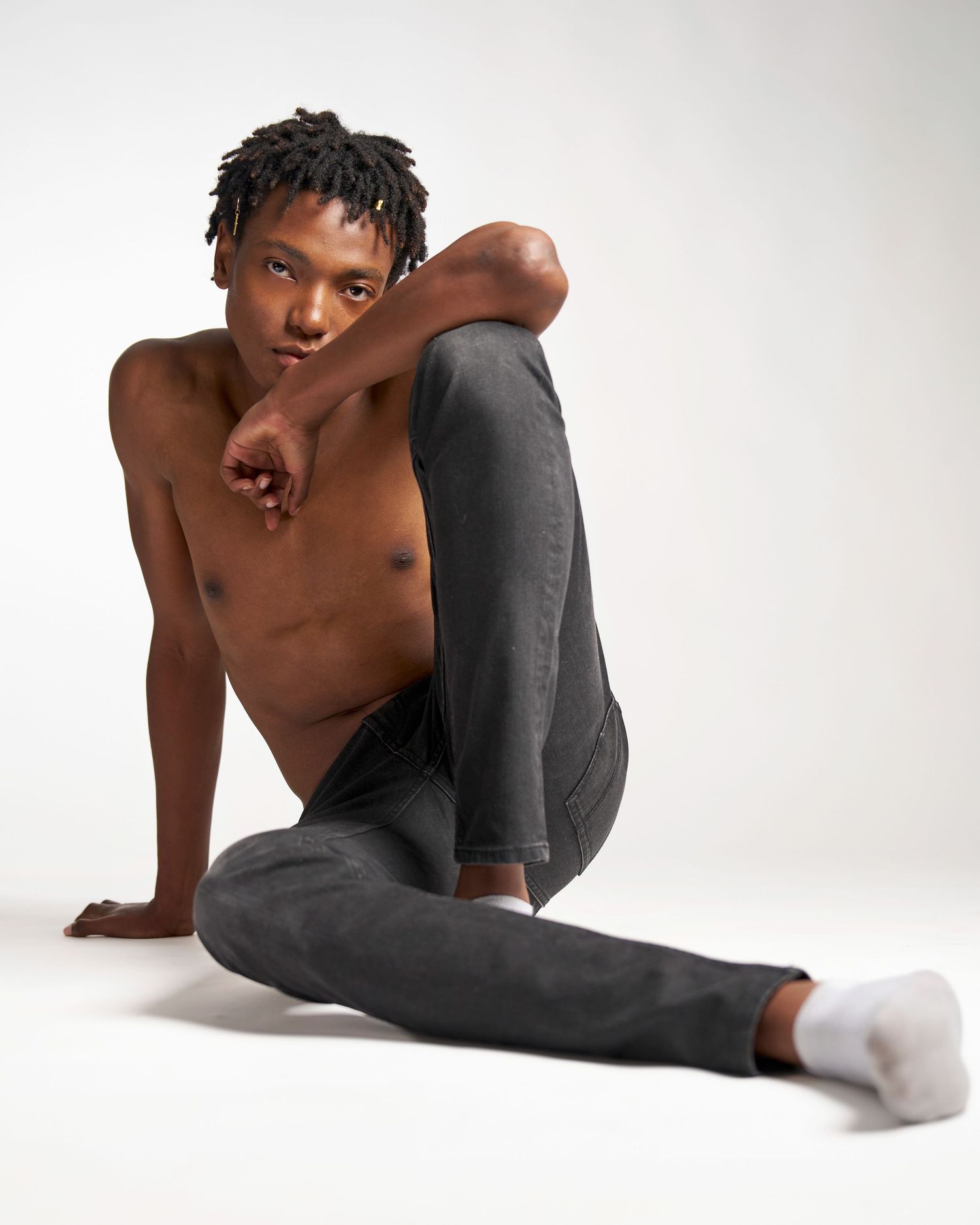 A series of artistic dance poses showing a performer in gray leggings and white socks against a white backdrop.